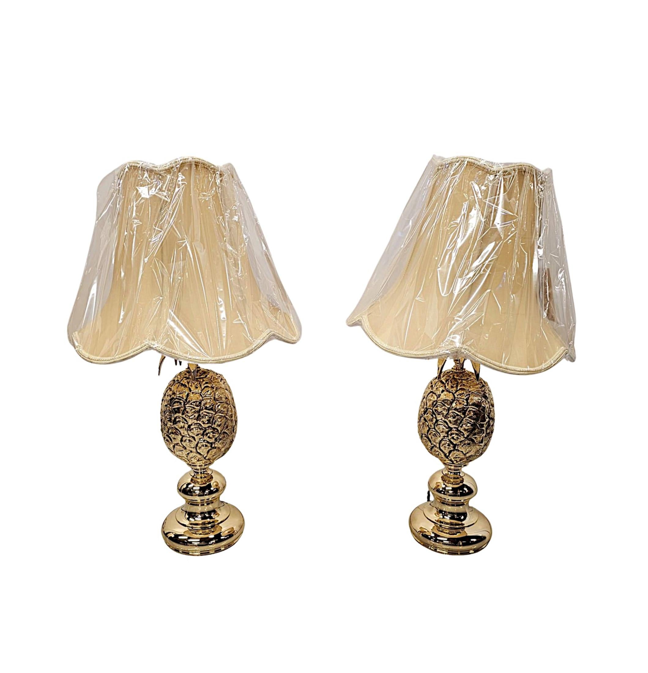 A very rare pair of 1970's polished brass pineapple table lamps, rewired and of exceptional quality.  The stunningly embossed pineapple is surmounted with a finely cast arrangement of leaves, supported on an elegant socle plinth base. 

Lamp shades