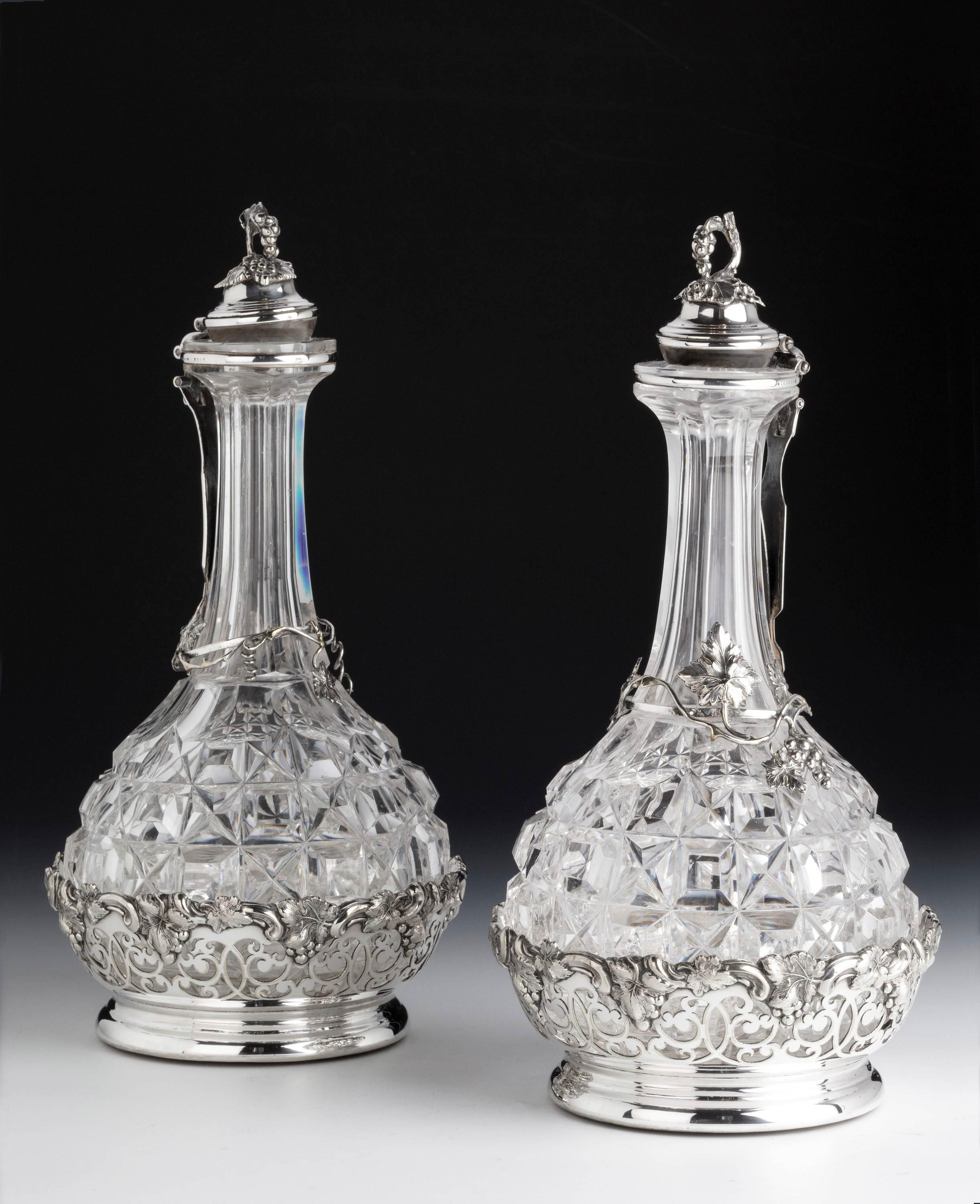 A very rare pair of heavily cut glass wine decanters in their original pierced and chiselled cradles. The tops cantilevered with ball-glass fittings. Of the very finest quality.