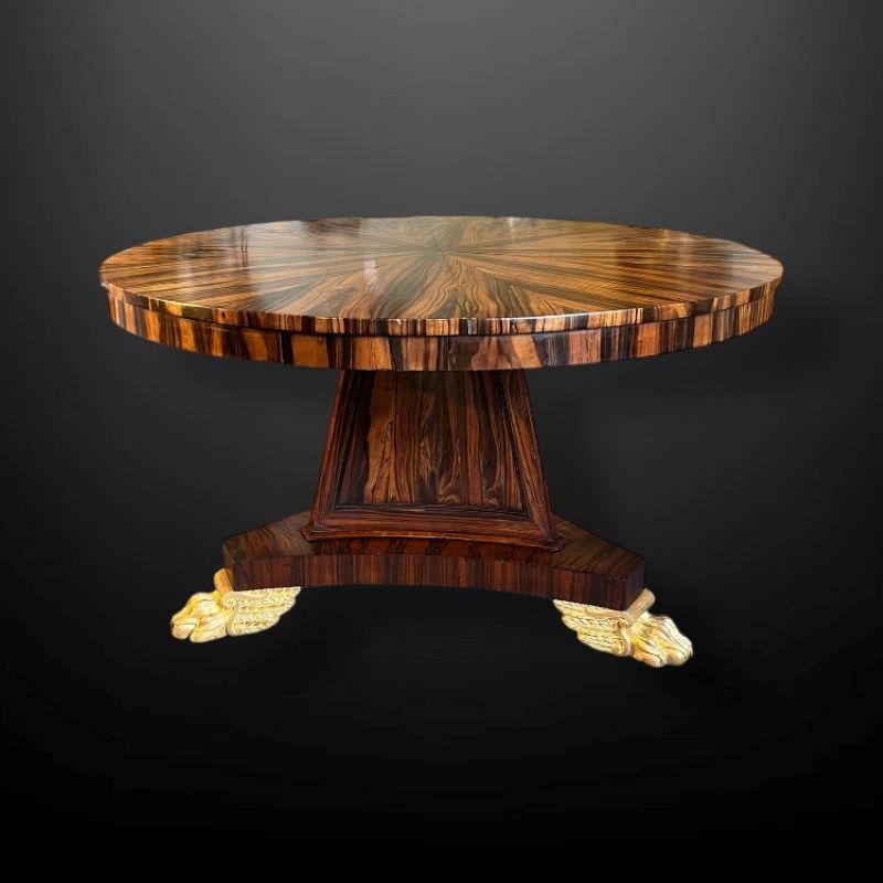 A very striking Regency Coromandel Centre Table with gilt paw feet.

The circular top featuring a highly decorative natural coramandel wood veneer. The vibrant pattern of the wood is also finished all the way around on the apron.

The top rests on