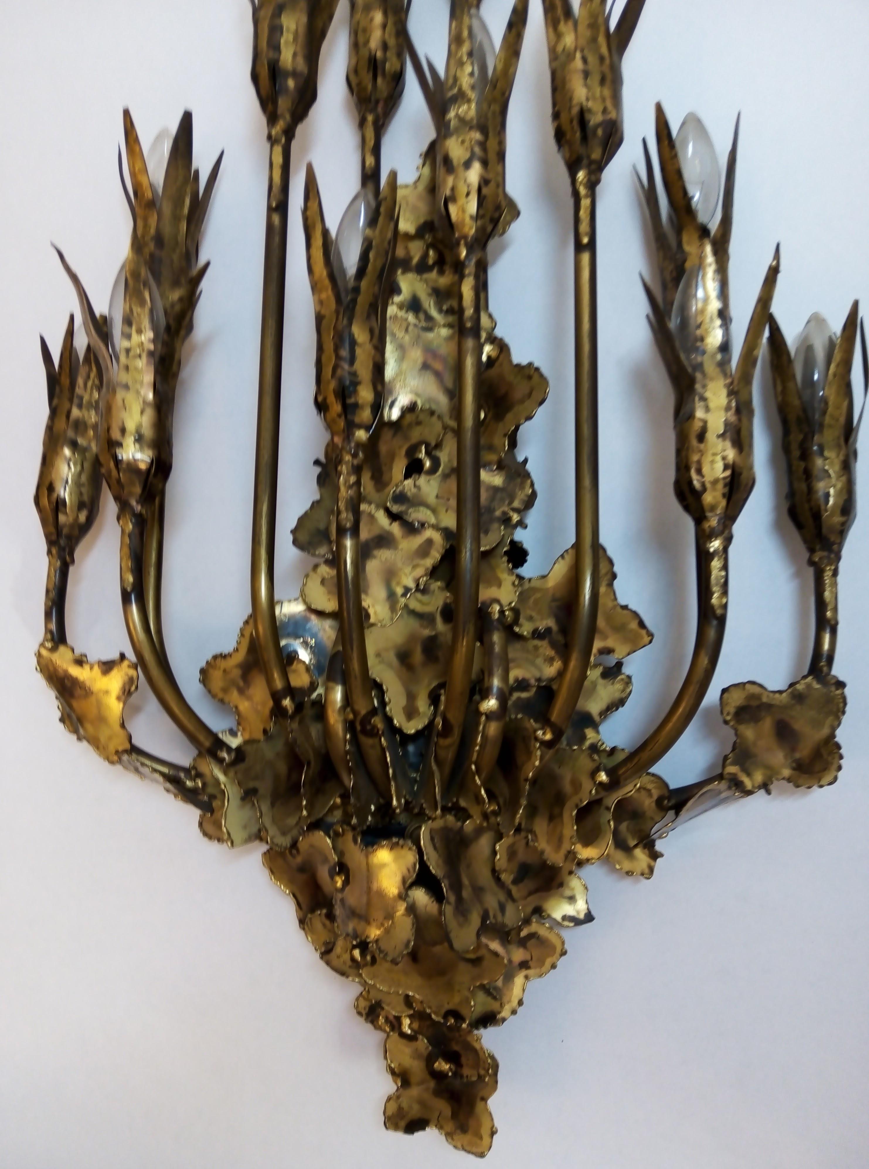 A very unique 12-arm wall sconce in torch-cut metal with floral motifs and multiple layers of leaves designed by Tom Greene and manufactured by Feldman Lighting Company in Los Angeles, Calif. in the 1960s. Definitely a 