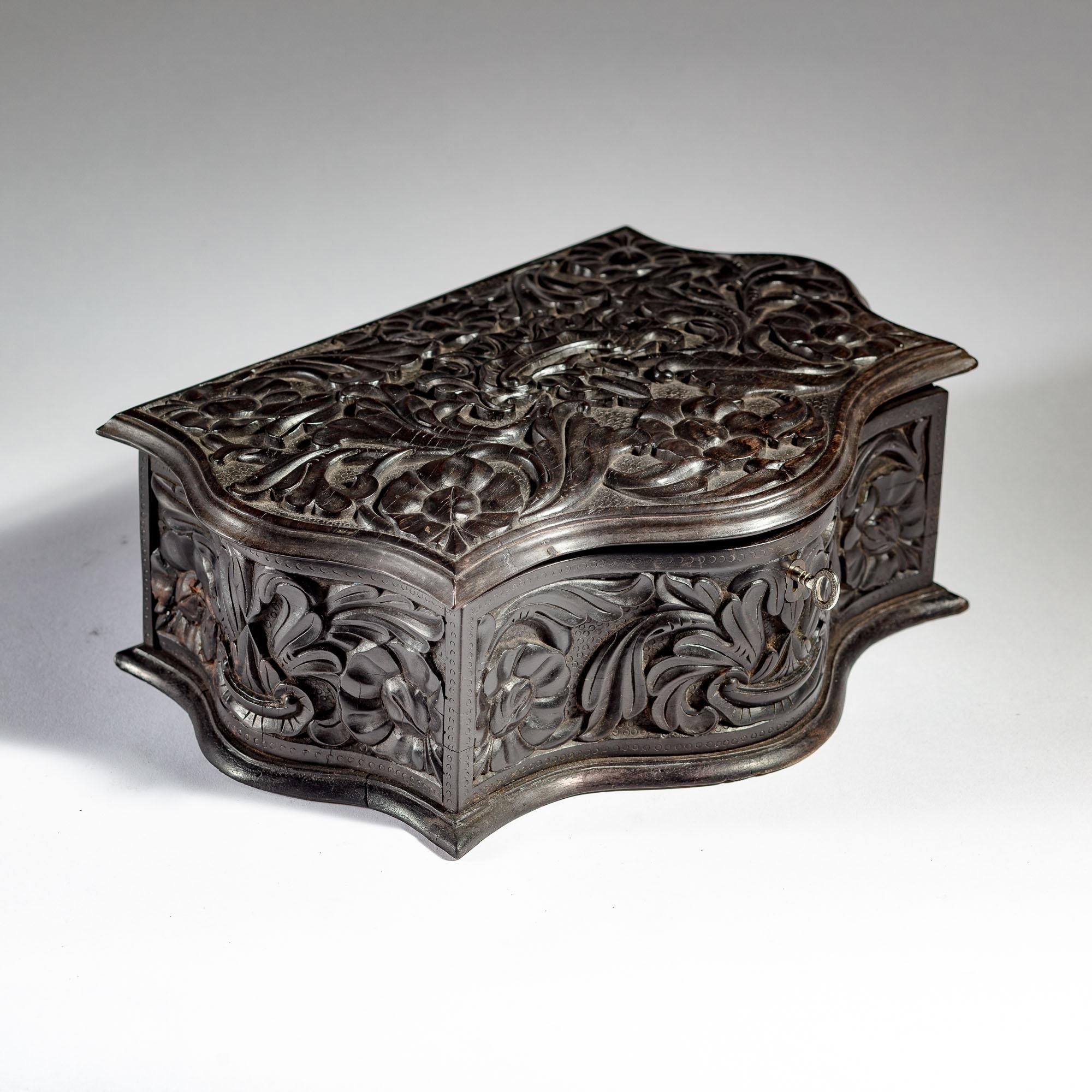 A very unusual mid 19th century carved ebony workbox, with a highly pronounced scalloped outline, the top, and sides carved in high relief with floral and foliate detail on a stamped ground. Opening to a void with brass hinges and mounts, the inside