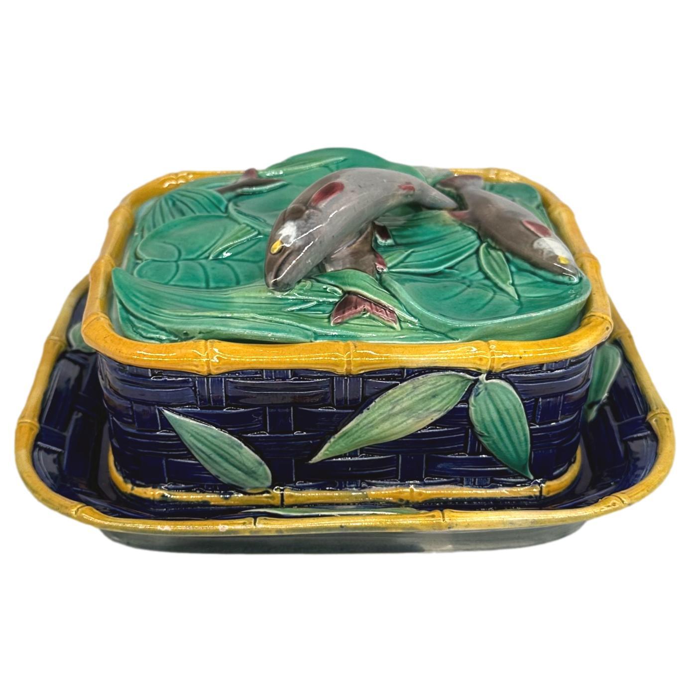 A Rare Victoria Pottery Company Majolica Sardine Box with five sardines on green glazed lotus pads and other foliage, trimmed in yellow bamboo with green shoots, the body and integral underplate are molded as a cobalt-glazed woven basket.  The