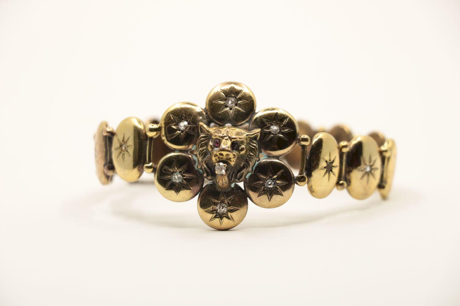 A Victorian 9K Gold Diamond Lion Head Bracelet 
Highlighting a Lion's Head mounted in Center with Red Gemstone eyes and Diamond in mouth. 

Approximate Dimensions:
18.2 cm ( Length)
1.5 cm - 3.4 cm (Width) 
13.1 grams in weight.