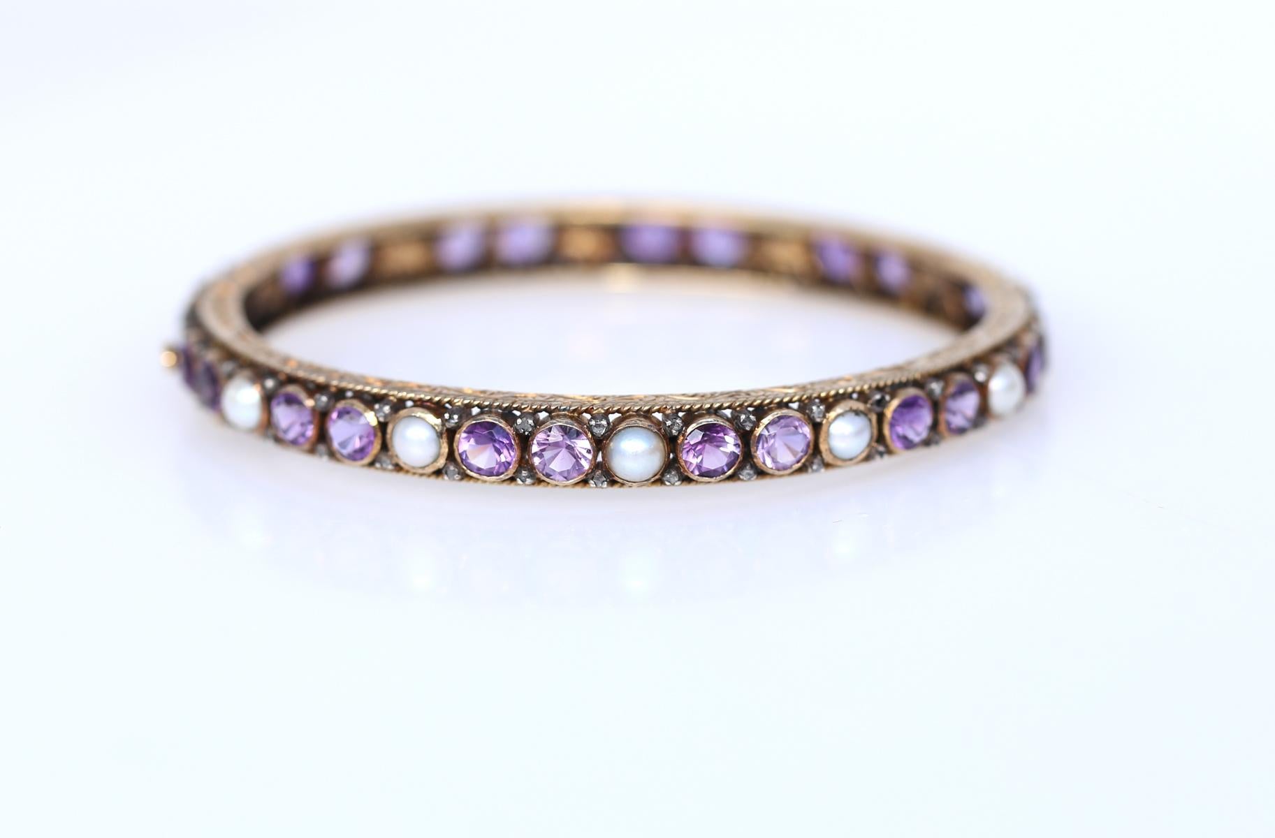 A Victorian Amethyst and Pearl bangle bracelet in yellow gold, the hinged body set with a row of round cut amethysts and pearls. Austrian assay marks. An absolutely wonderful item and a great example of its time. The design is so well judged and
