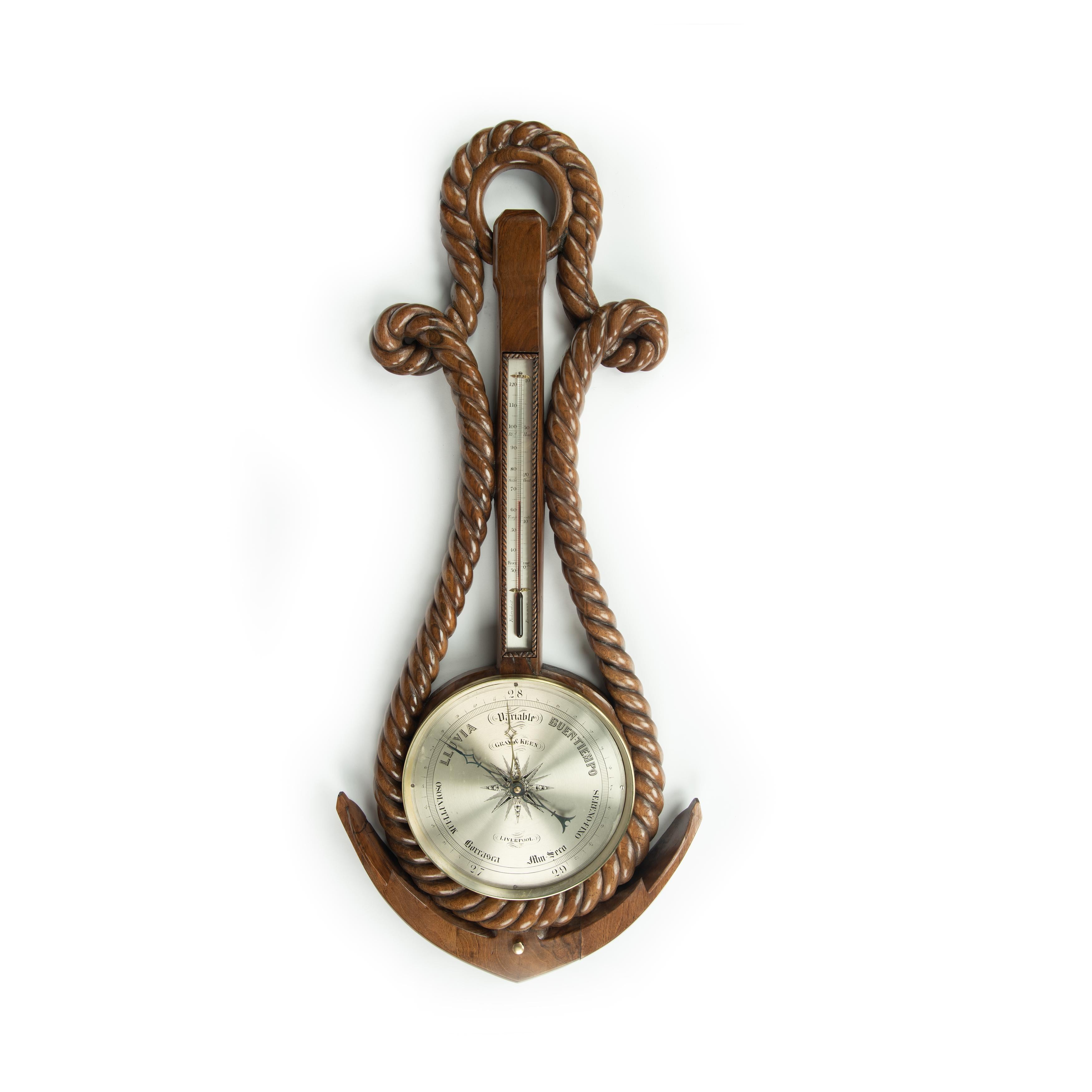 A Victorian anchor and rope barometer by Gray and Keen, Liverpool. The 10 ¾-inch silvered dial of this walnut barometer is set within the arms of an anchor and a coil of double twisted rope which passes over a ring handle.  The dial is inscribed in