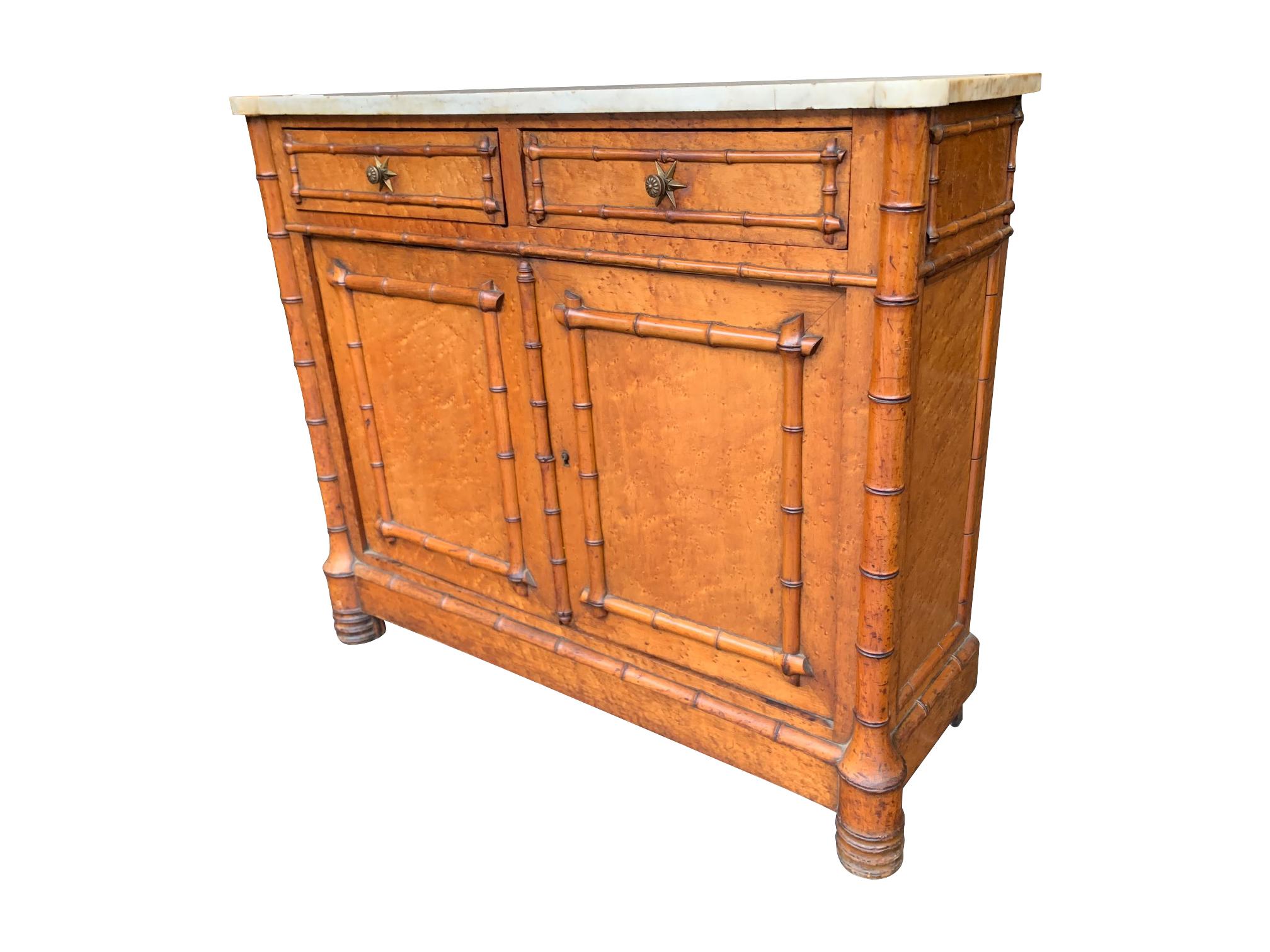 A lovely Victorian bird's-eye maple console cabinet with faux bamboo detail on the doors, corners and sides mounted with shaped white marble top. With two drawers with original brass star shaped knobs and twin lower cupboards.