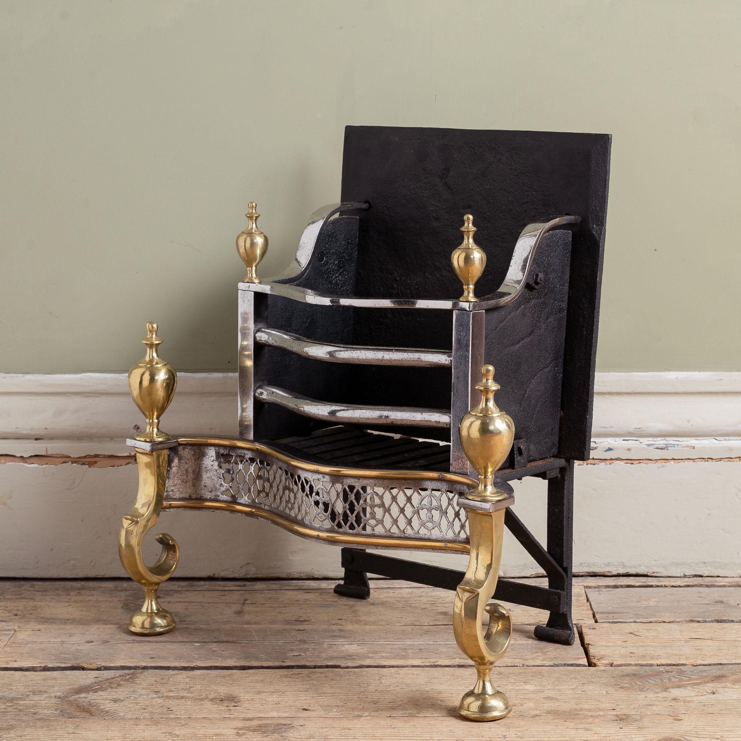 A Victorian brass, iron and steel fire grate, in the George III style, with polished steel fret-cut apron, scrolled standards and bold urn finials. Restored.

Dimensions:	60cm (23½