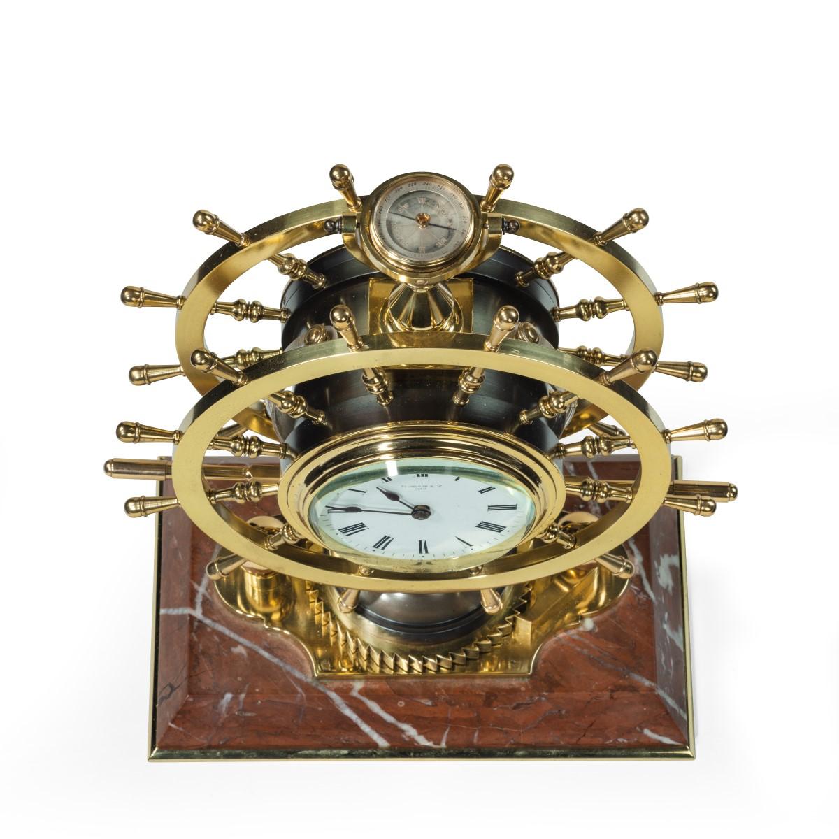 A Victorian brass novelty clock by Elkington & Co., in the form of a double steering-wheel, one wheel enclosing a clock and the other a barometer, with two additional Fahrenheit thermometers attached to the curved sides, all surmounted by a