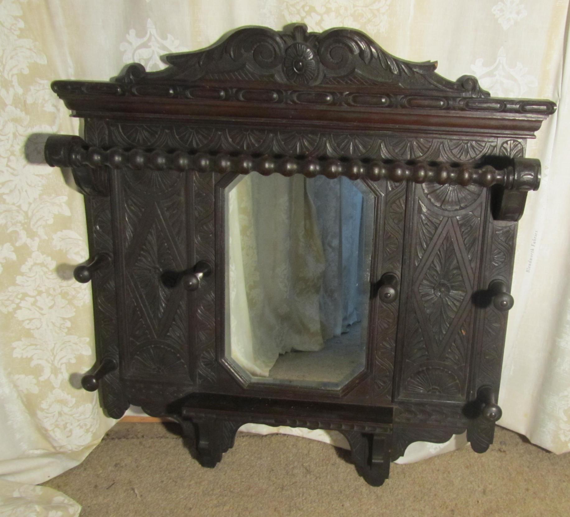 A Victorian Carved Oak Hall Mirror with Hat and Coat Hooks

This is an unusual piece in the Gothic style, it is a wall hanging piece, it has 6 chunky turned wooden hooks for coats or hats and a bobbin turned rail to hang walking sticks or umbrellas