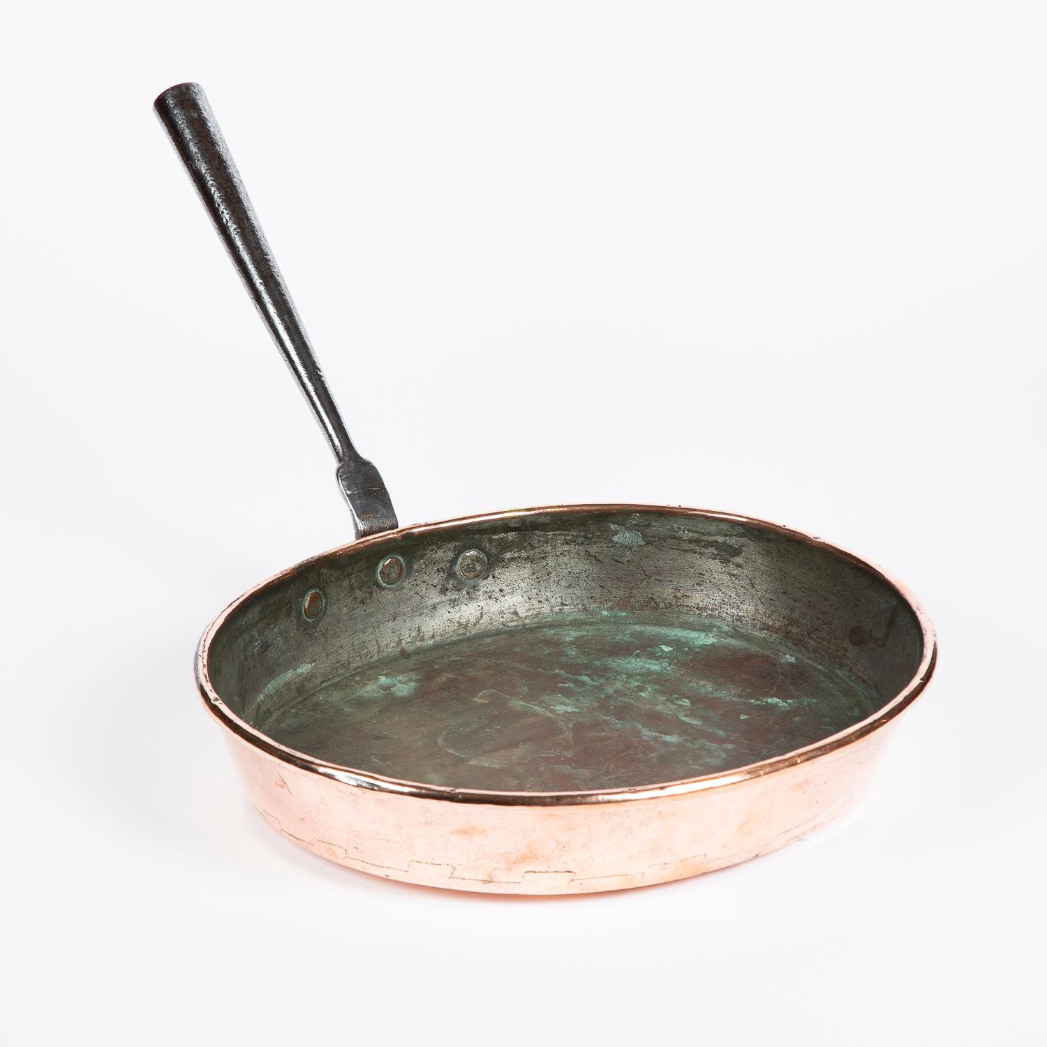 A large mid-19th century copper frying pan with riveted iron handle and seem base, circa 1860.

            