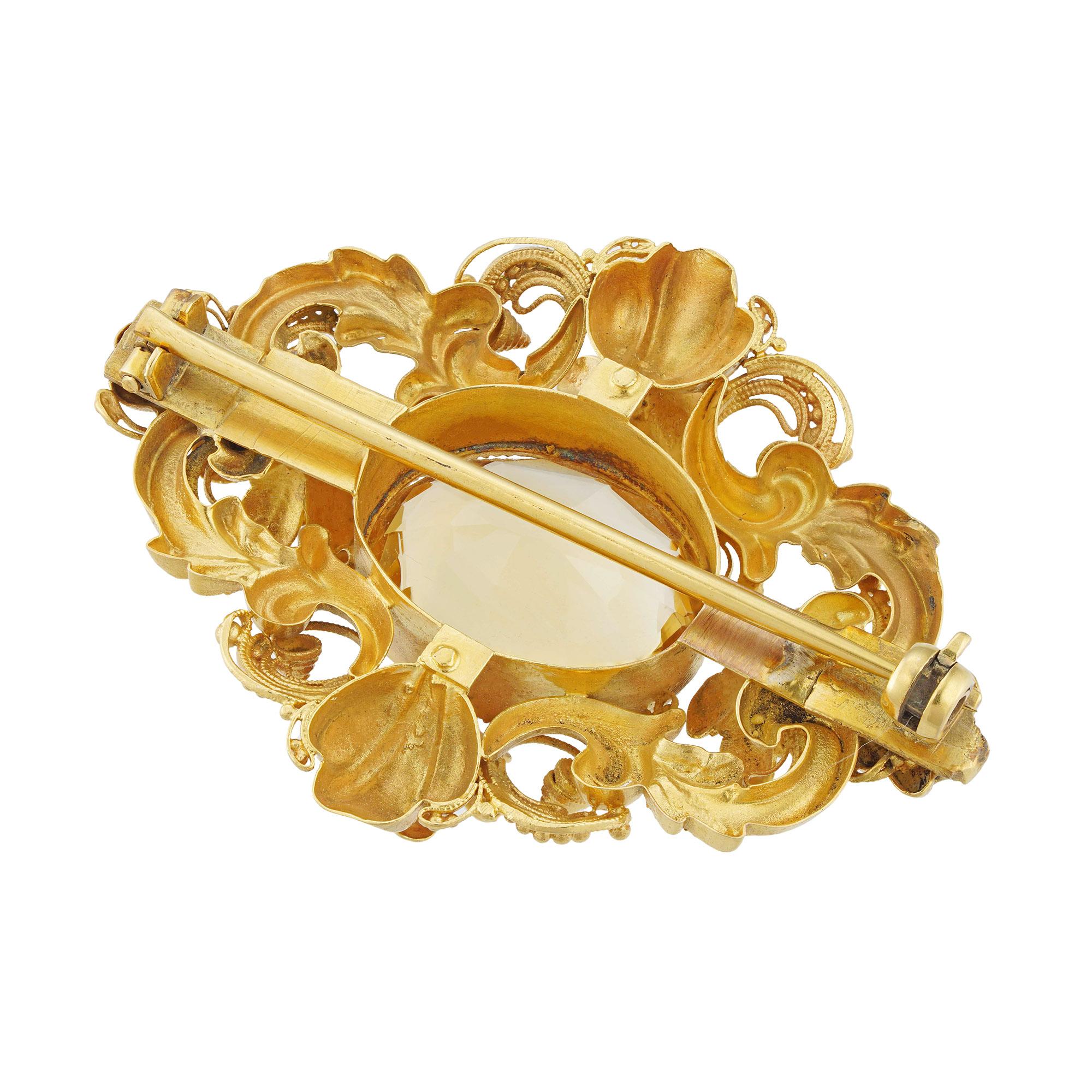 A Victorian citrine and gold brooch, the oval faceted citrine measuring approximately 1.5 x 1.3cm, surrounded by textured flower heads, foliate scrolls and cannetille decorations, mounted in yellow gold with gold pin fitting and later roller catch,