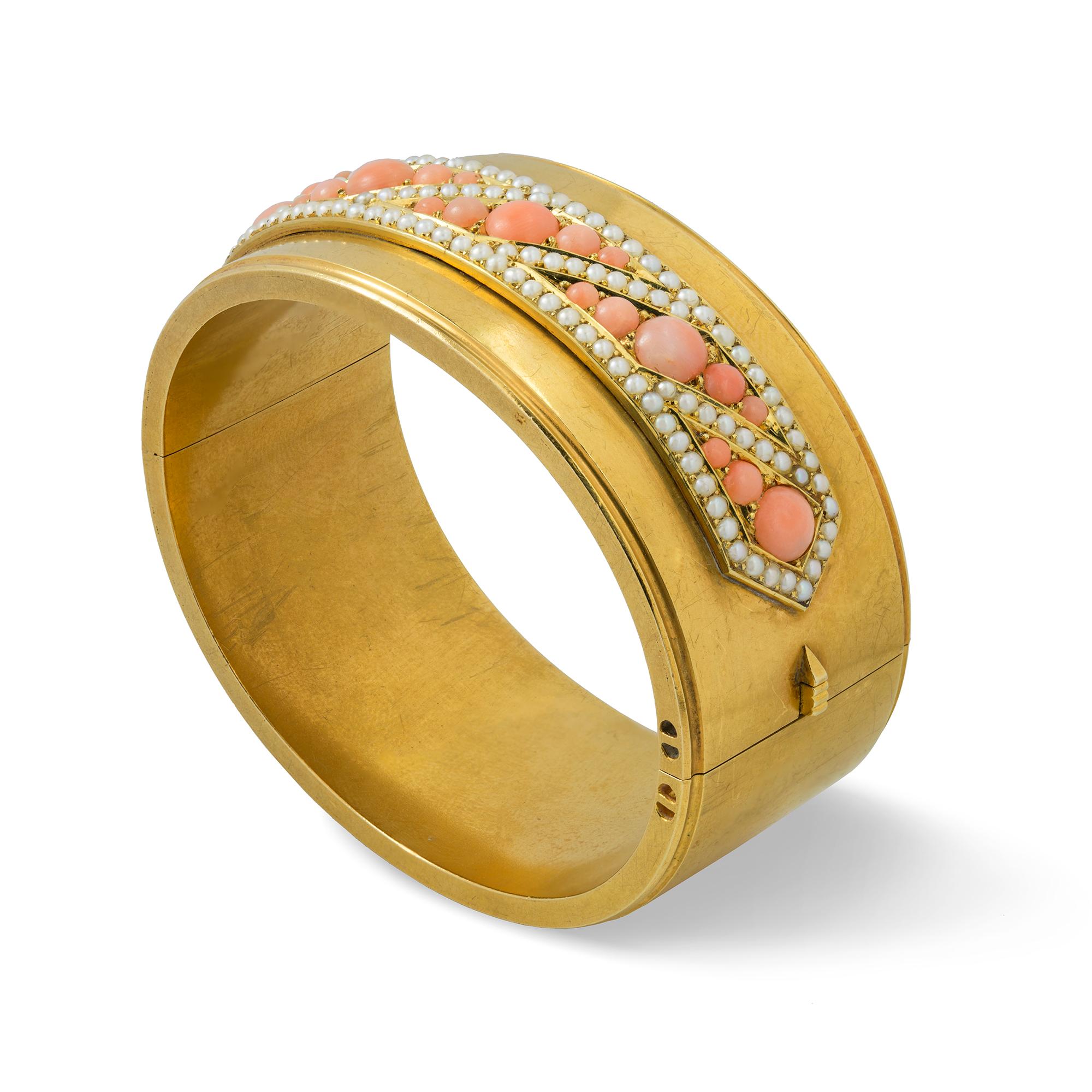 A Victorian coral and pearl gold bangle, the front side with a hexagonal panel set with cabochon-cut pink corals, surrounded by seed-pearl frame all set in a geometrical pattern, with a plain yellow gold back with hidden clasp, circa 1880, unmarked,