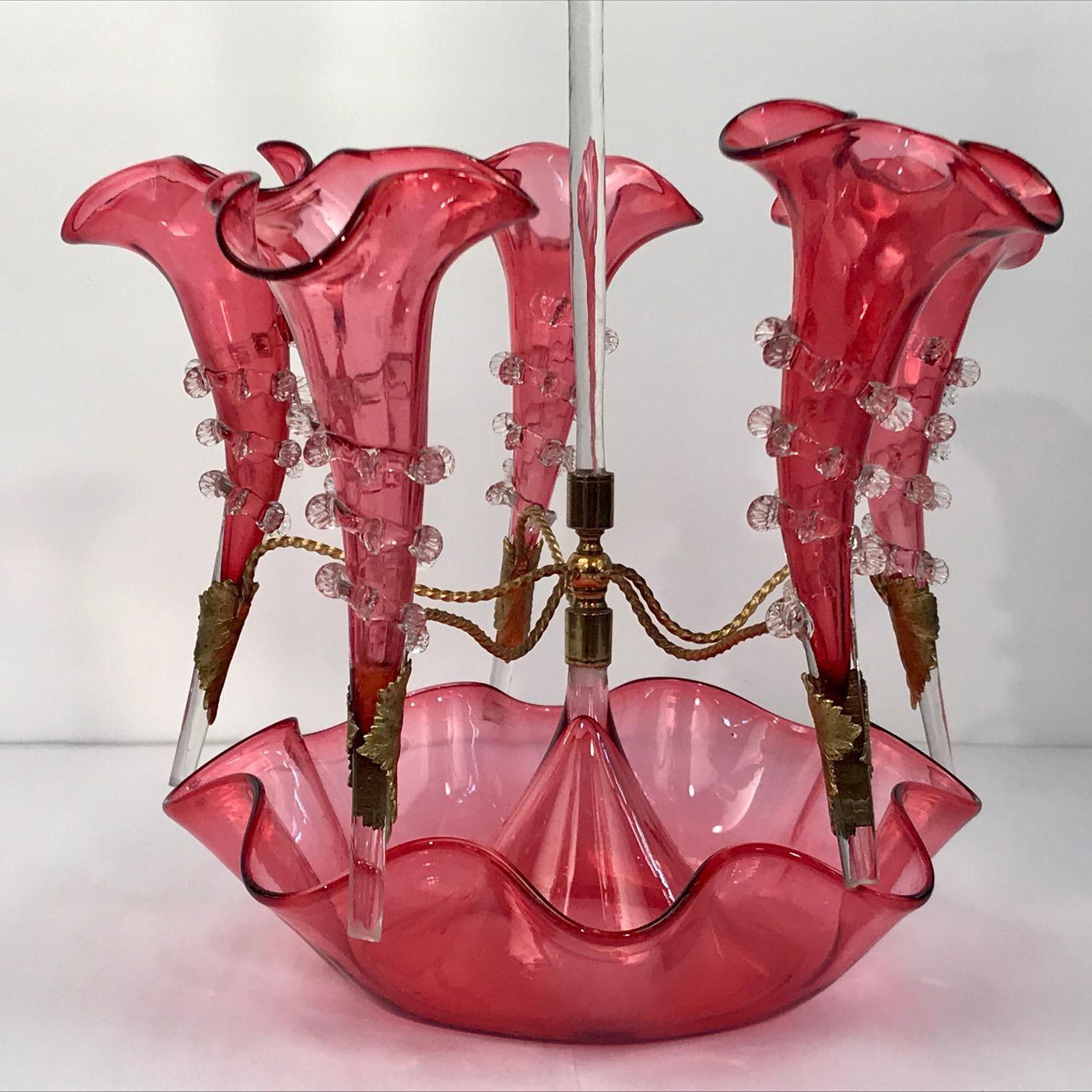This is a remarkably fine example in excellent condition. For both fruit and flowers, this hand-blown epergne has five trumpet-shaped vases around a larger central vase, all with frilled rims and applied wrythen clear ornament. The vases are