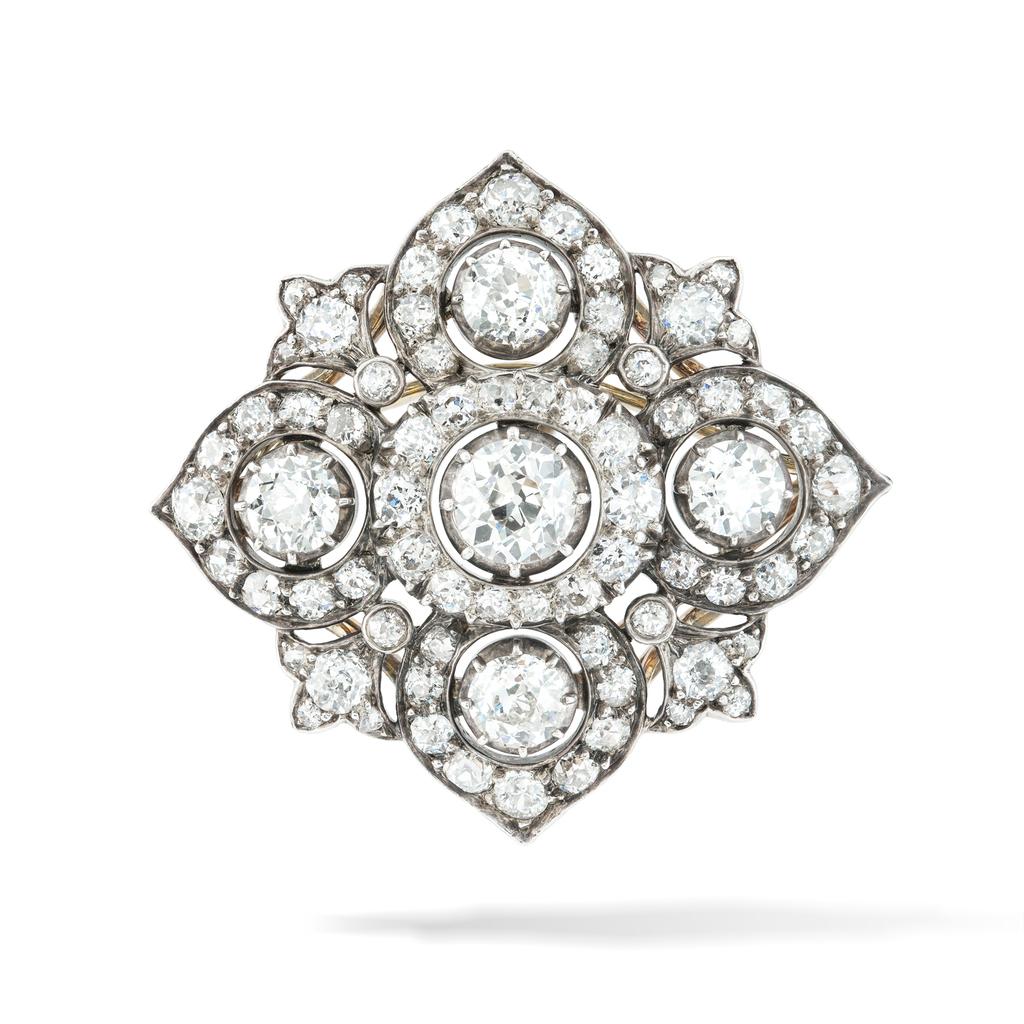 A Victorian diamond brooch pendant, the central diamond surrounded by an oval cluster formed of graduating old brilliant-cut diamonds, set between four petal-shaped diamond clusters and four fleur-de-lys diamond-set motifs, the diamonds weighing