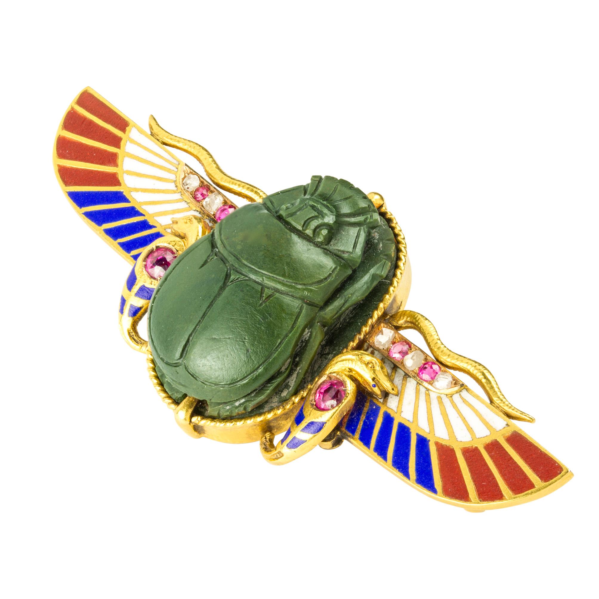 A Victorian Egyptian revival scarab brooch, the carved green hardstone scarab set within a gold wire frame to ruby set snakes and enamelled wings set with alternate rose-cut diamonds and rubies, all to a gold mount with engraved reverse and brooch