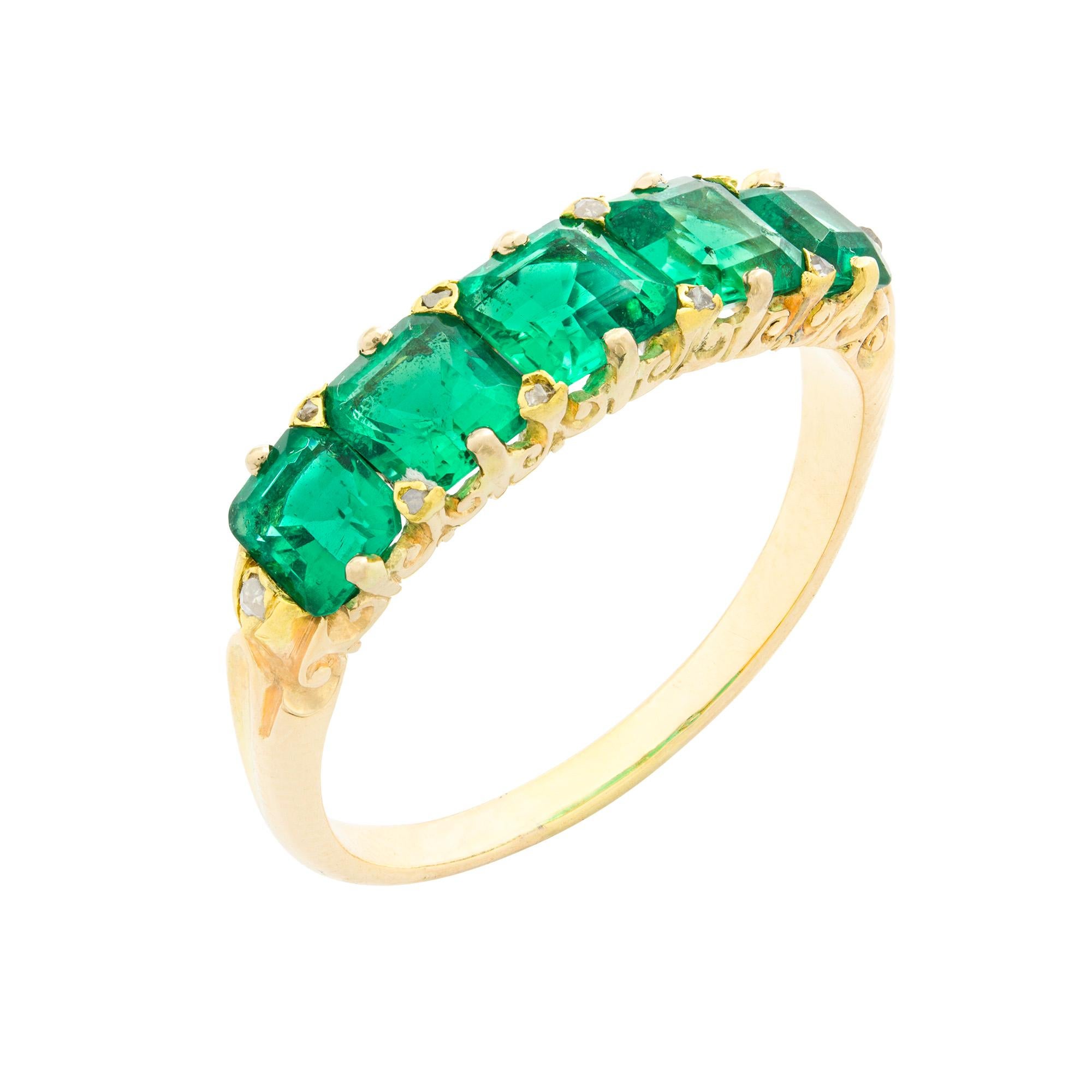 A Victorian five-stone carved half hoop emerald ring, the five emerald-cut emeralds estimated to weigh a total of 1.80 carats, graduating in size from the centre with two rose-cut diamonds set between each, all claw-set to a yellow gold carved half