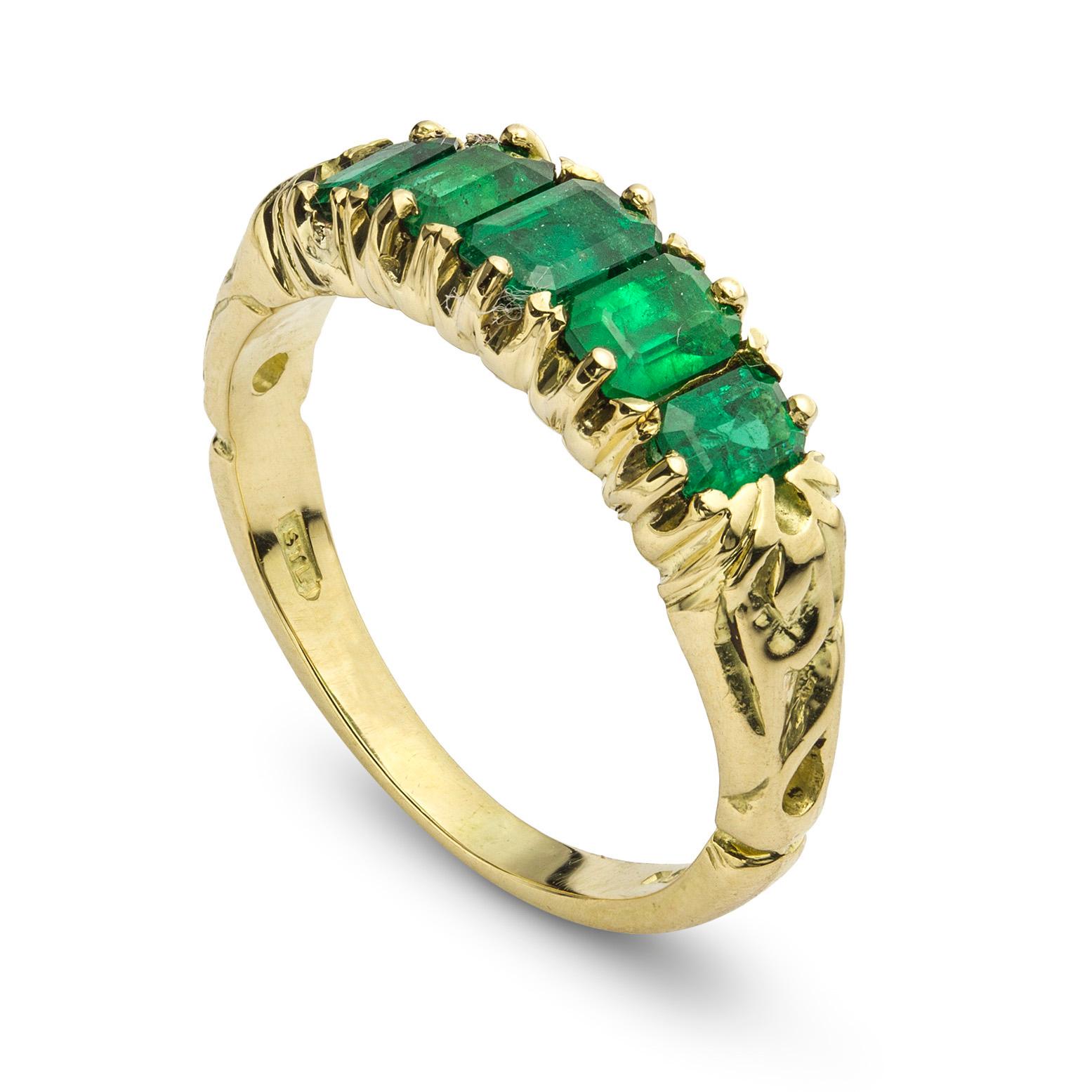 A Victorian five stone emerald ring, the five emerald-cut emeralds graduating from the centre and weighing 1.1 carats in total, claw set to an 18ct yellow gold mount with carved open shoulders, circa 1890, later hallmarked 18ct gold London, head