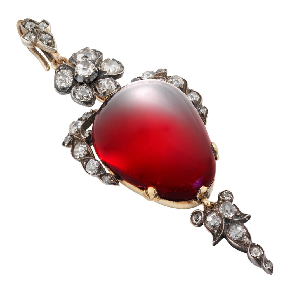 A Victorian garnet and diamond pendant, the inverted pear-shaped cabochon garnet surmounted by a floral and foliate spray and suspending a foliate drop, set throughout with old brilliant-cut and single cut-diamonds, to a delicately set in silver to