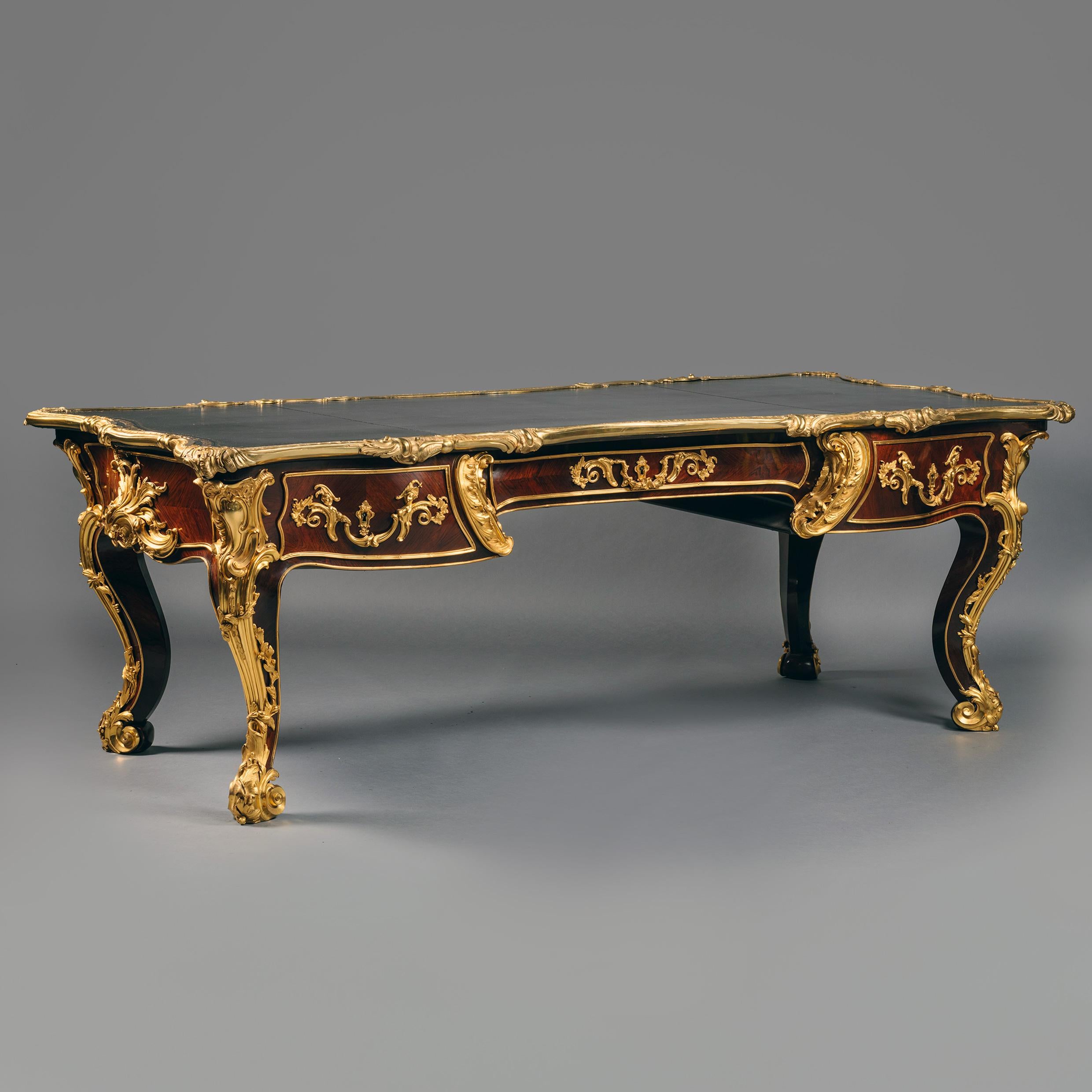 A Palatial Victorian Gilt-Bronze Mounted Bureau Plat.

This palatial bureau plat is of grand proportions. The top is of serpentine rectangular out-shape and is lined in dark green leather with a beautiful gilt-tool embossed border. The top rim is 