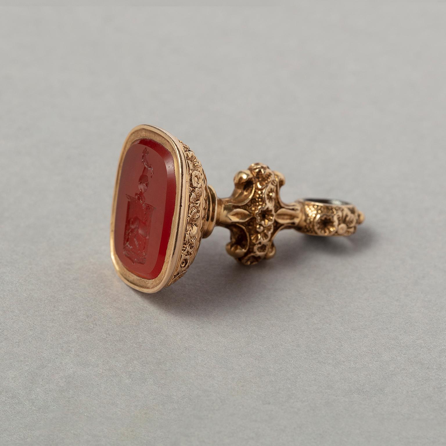 An 18 carat yellow  gold fob seal lavishly decorated with flowers set with a carnelian seal with a coat of arms featuring a helm with  a stepping horse and a crest with a staggering horse.  European, 19th century.

weight: 12 grams
dimensions