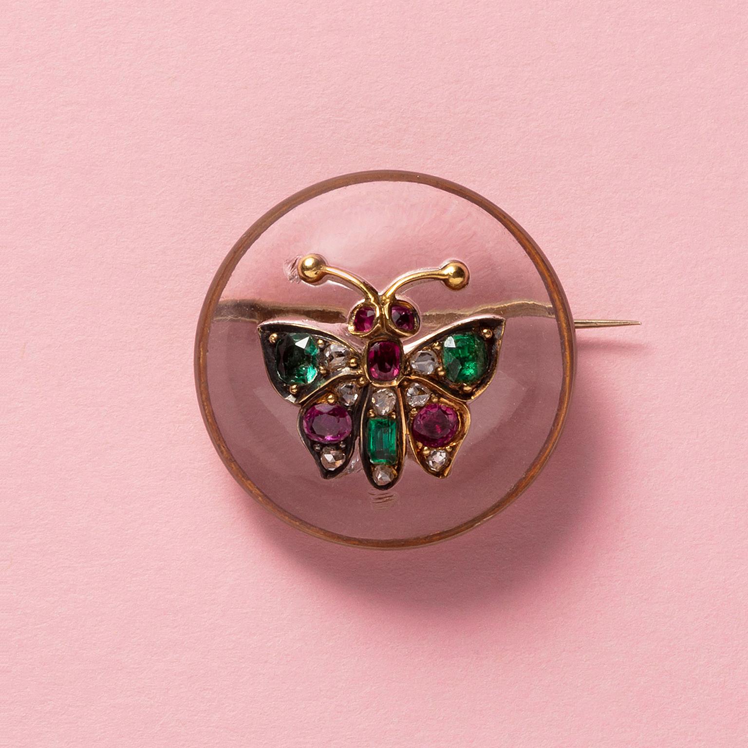 A 14 carat gold butterfly brooch with a large, round cabochon cut rock crystal set with a gold butterfly set with old cut emeralds, rubies and diamonds, the pin is 9 carat gold, circa 1880.

weight: 13.20 grams
diameter: 27 mm