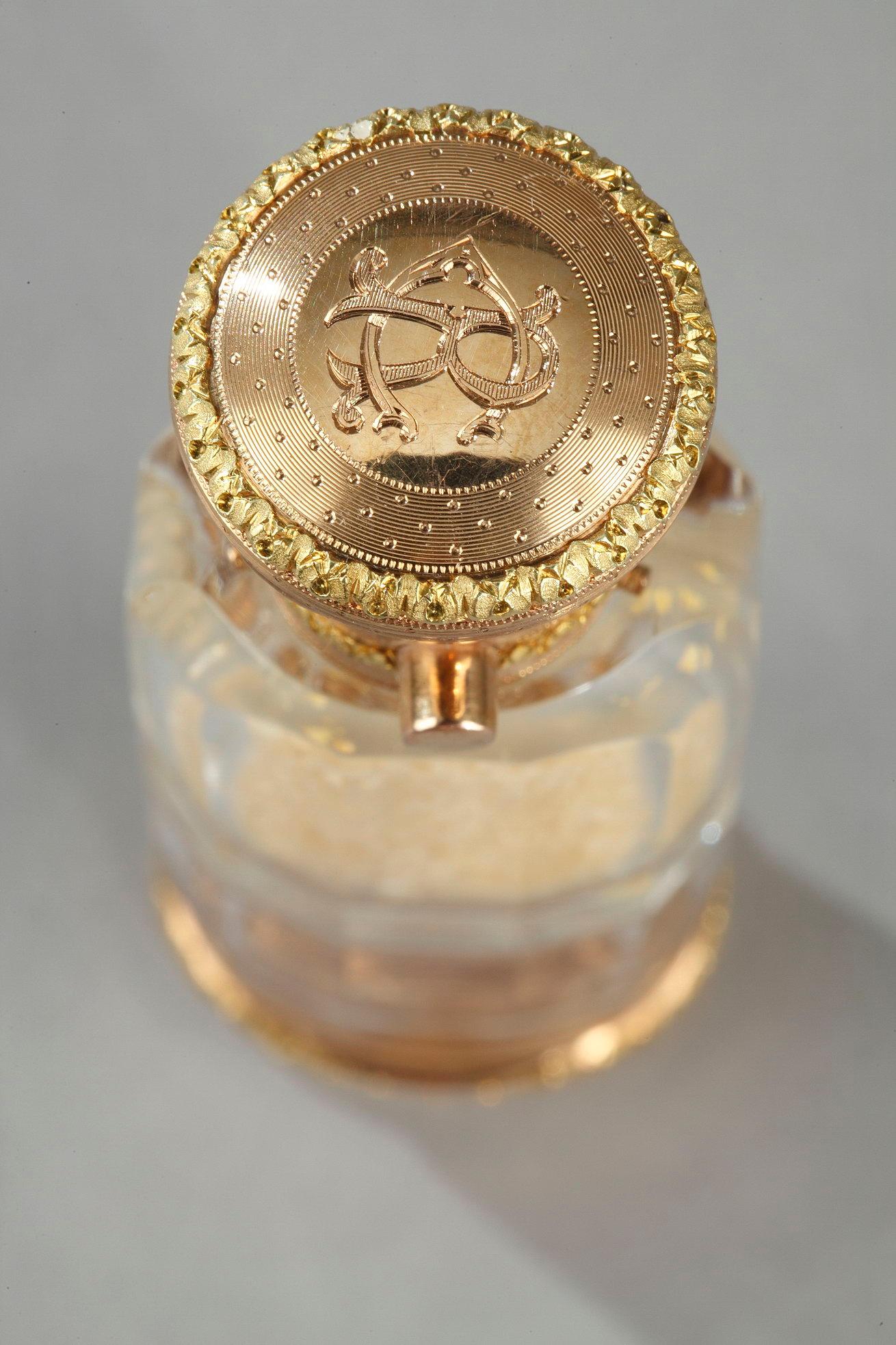 A cylindrical, double-ended transparent crystal perfume bottle with one side  a fine vinaigrette and the other a smelling salt compartiment. The vinaigrette opens a pierced grid still containing its sponge soaked in flavored vinegar. The gold