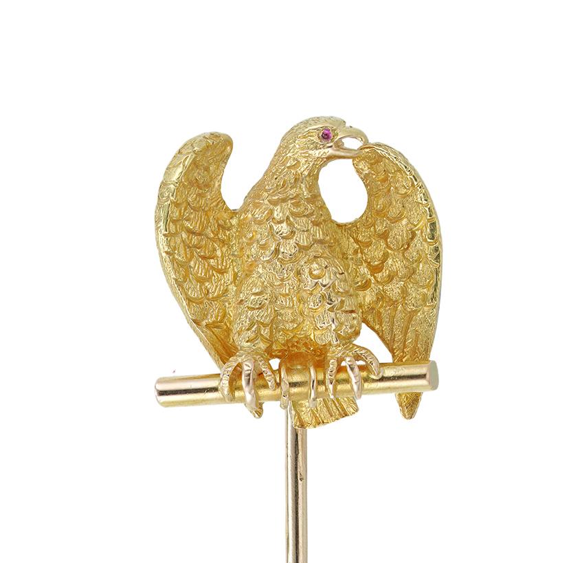 A Victorian gold eagle stick-pin, the realistically carved eagle sitting on a branch, with a round cabochon-cut ruby-set eye, mounted in yellow gold with a gold-pin, circa 1880, the jewelled part measuring 1.5x1.6cm, gross weight 4.6 grams.

This