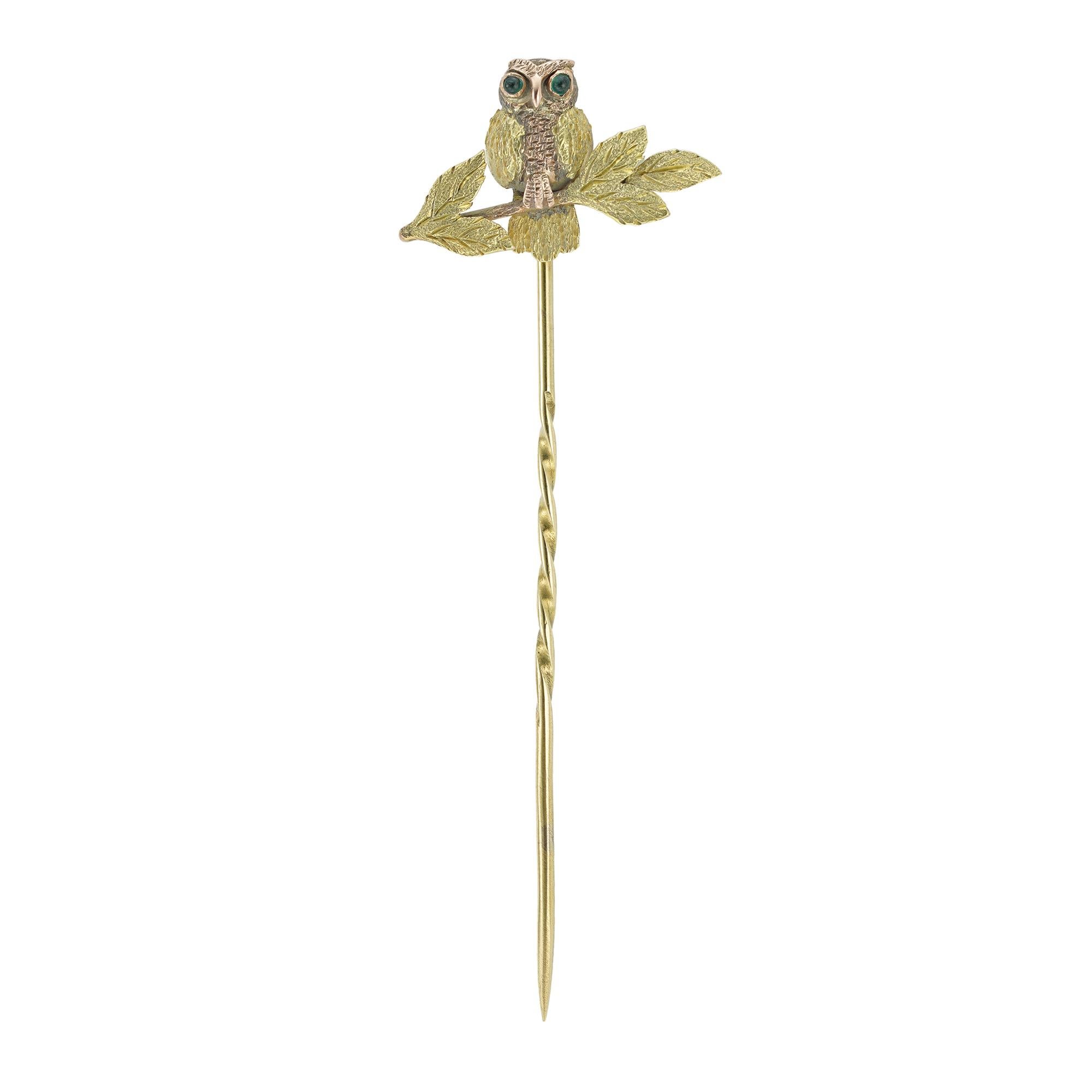 A Victorian gold owl stick-pin, the two-colour gold owl sitting on a branch with leaves, set with two cabochon-cut emerald-set eyes, all made in gold marked 9ct, with gold pin fitting, circa 1890, the jewelled part measuring 2.1 x 0.8cm, gross