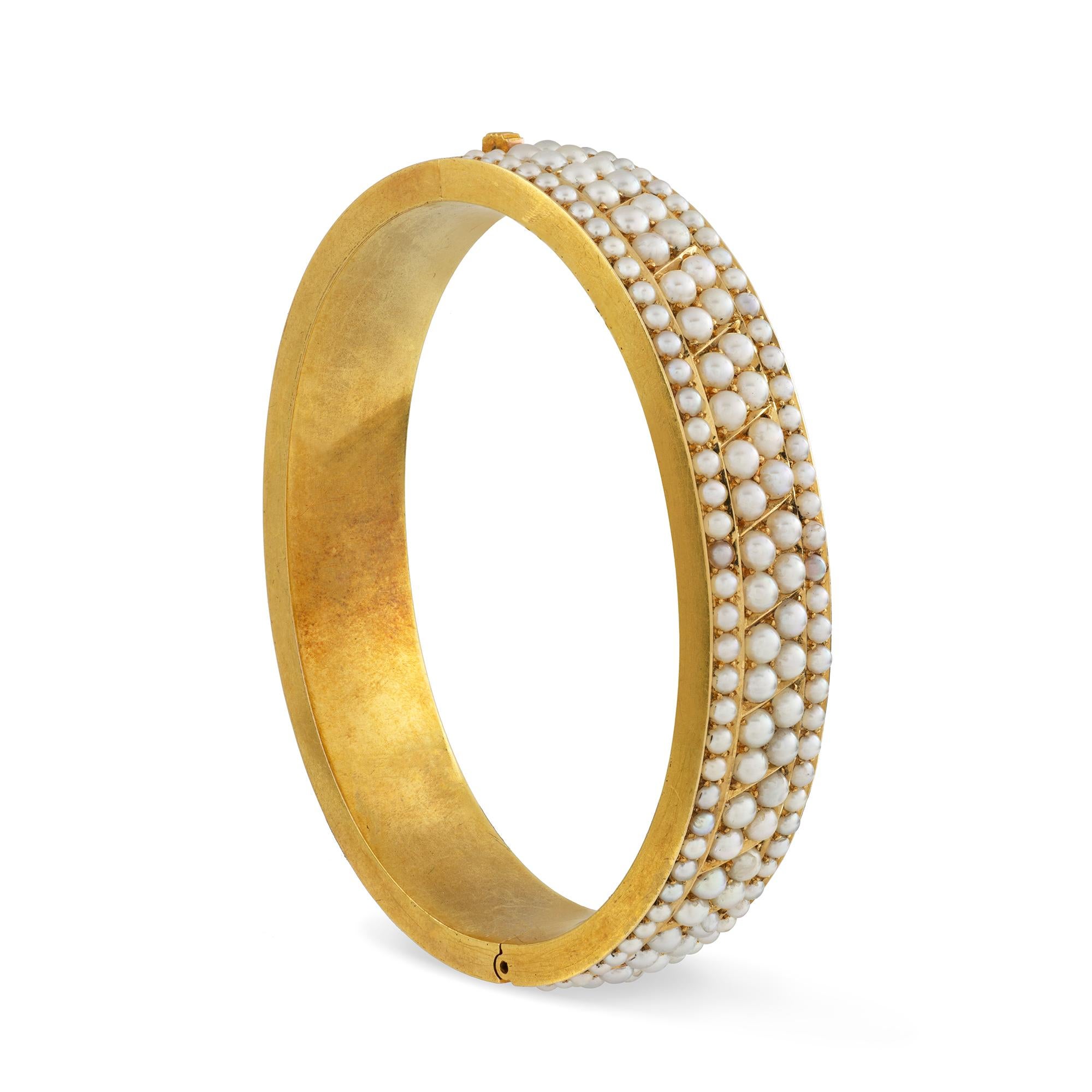 A Victorian half-pearl hinged bangle, the front set with four rows of half pearls, the two central row of pearls measuring 3mm and the two outer rows of pearls measuring 2mm, the back of yellow gold with matt finish, with integral clasp and safety