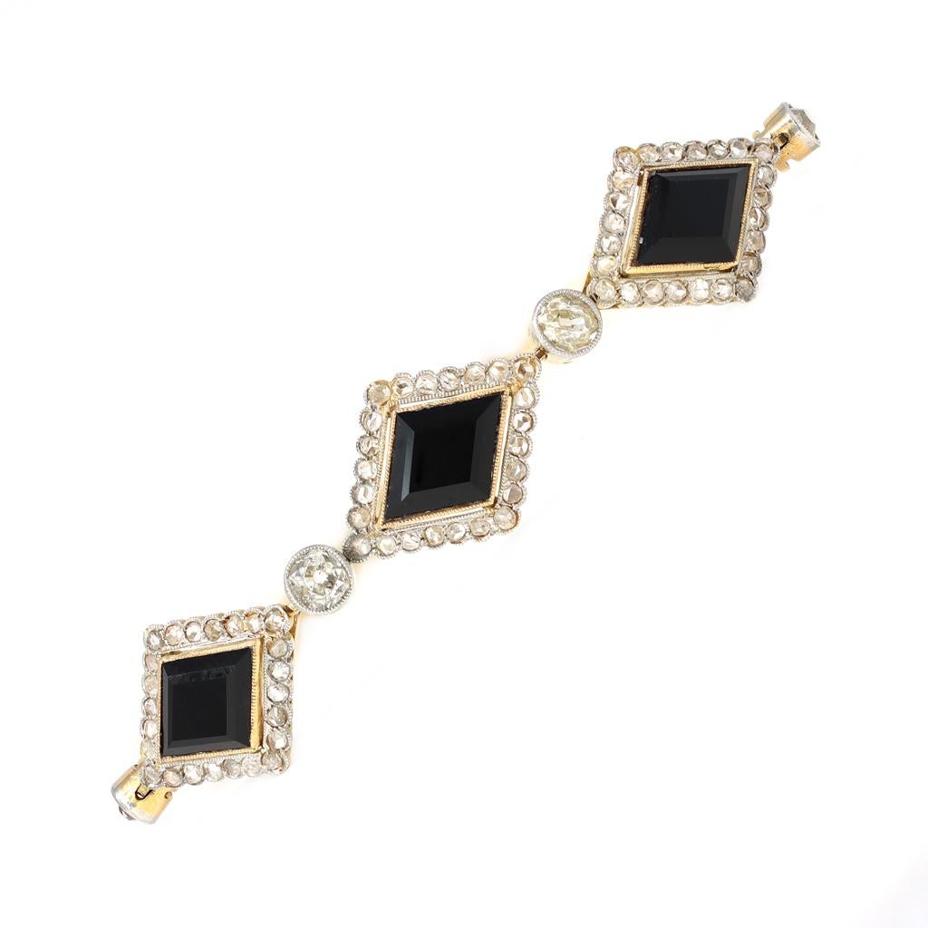 A Victorian Onyx and Diamond bracelet in 18K gold from the late 19th century. The bracelet features 3 lozenge shape Onyx each surrounded with a halo of rose cut diamonds. The lozenges are spaced with a bezel set old mine cut diamond. The estimated