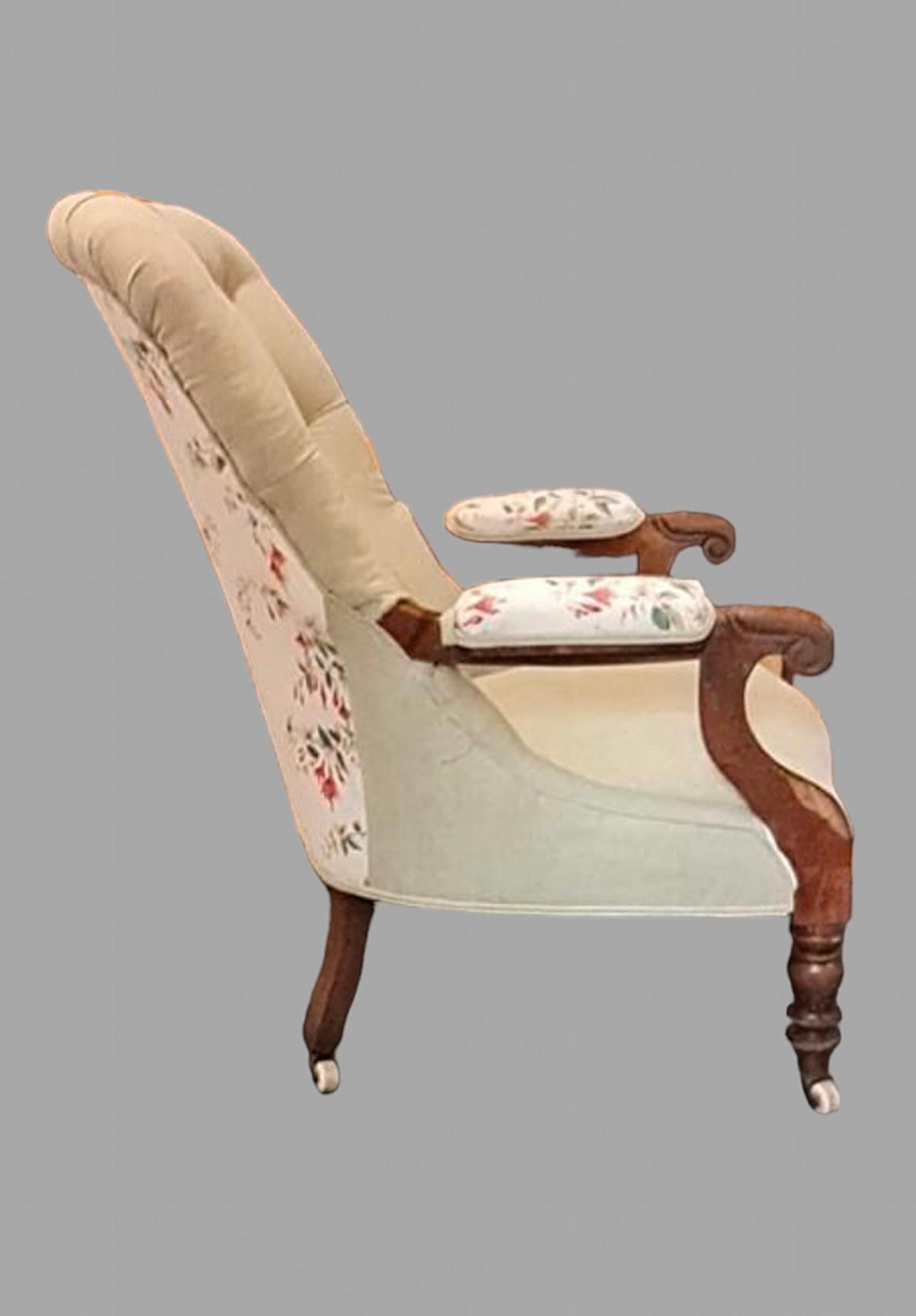 A Victorian Mahogany Framed Button Back Armchair recovered in a green linen with contrast buttons and a Colefax and Fowler Fushica patterned fabric on the arms and back legs leading to ceramic castor legs. Seat Height 45 cm.