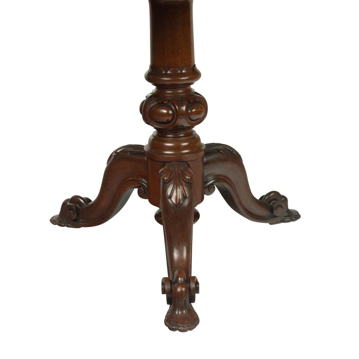 A Victorian mahogany revolving display table, the circular burgundy leather inset top within cross banding, the frieze also cross-banded, the whole raised upon a turned support with three cabriole legs carved with scrolling acanthus and volutes.