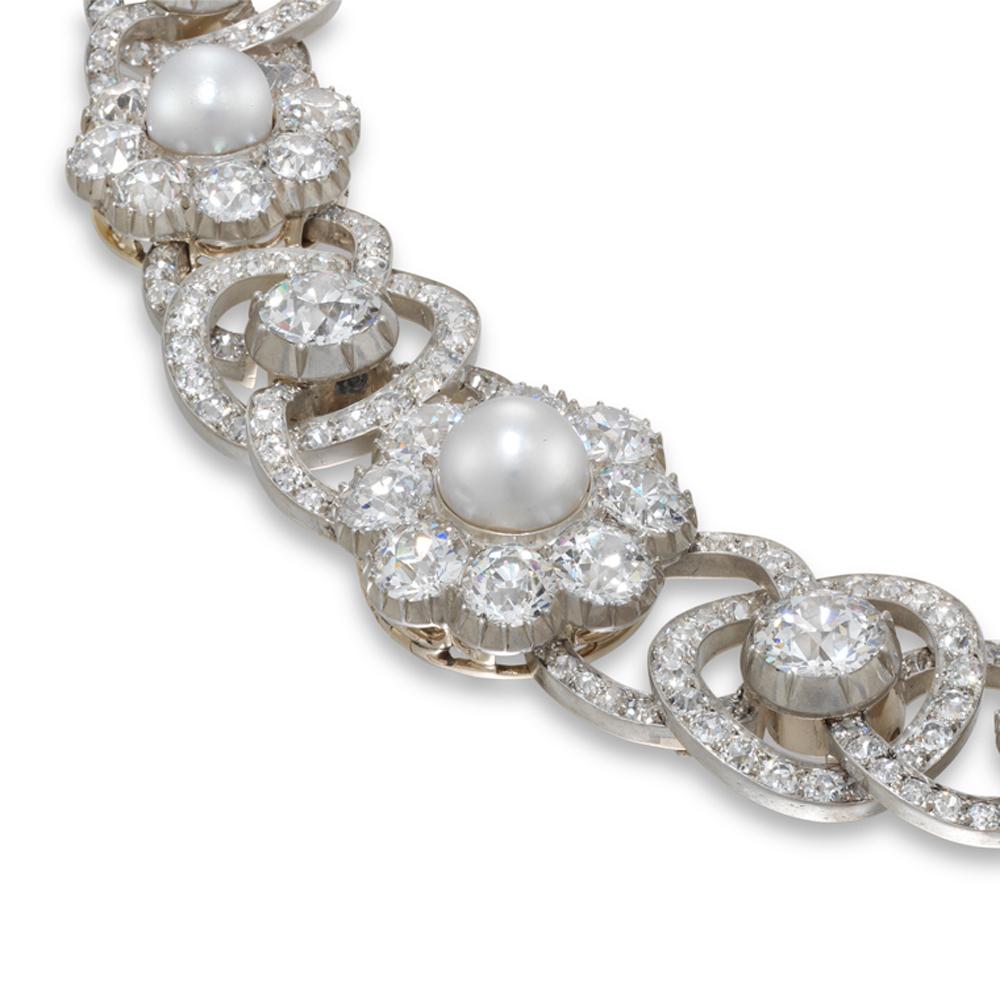 A Victorian natural pearl and diamond necklace, the twelve graduated cluster motifs each centred with natural bouton pearls measuring from 5.6 mm to 9 mm, within a surround of old brilliant-cut diamonds in cut-down silver setting alternately