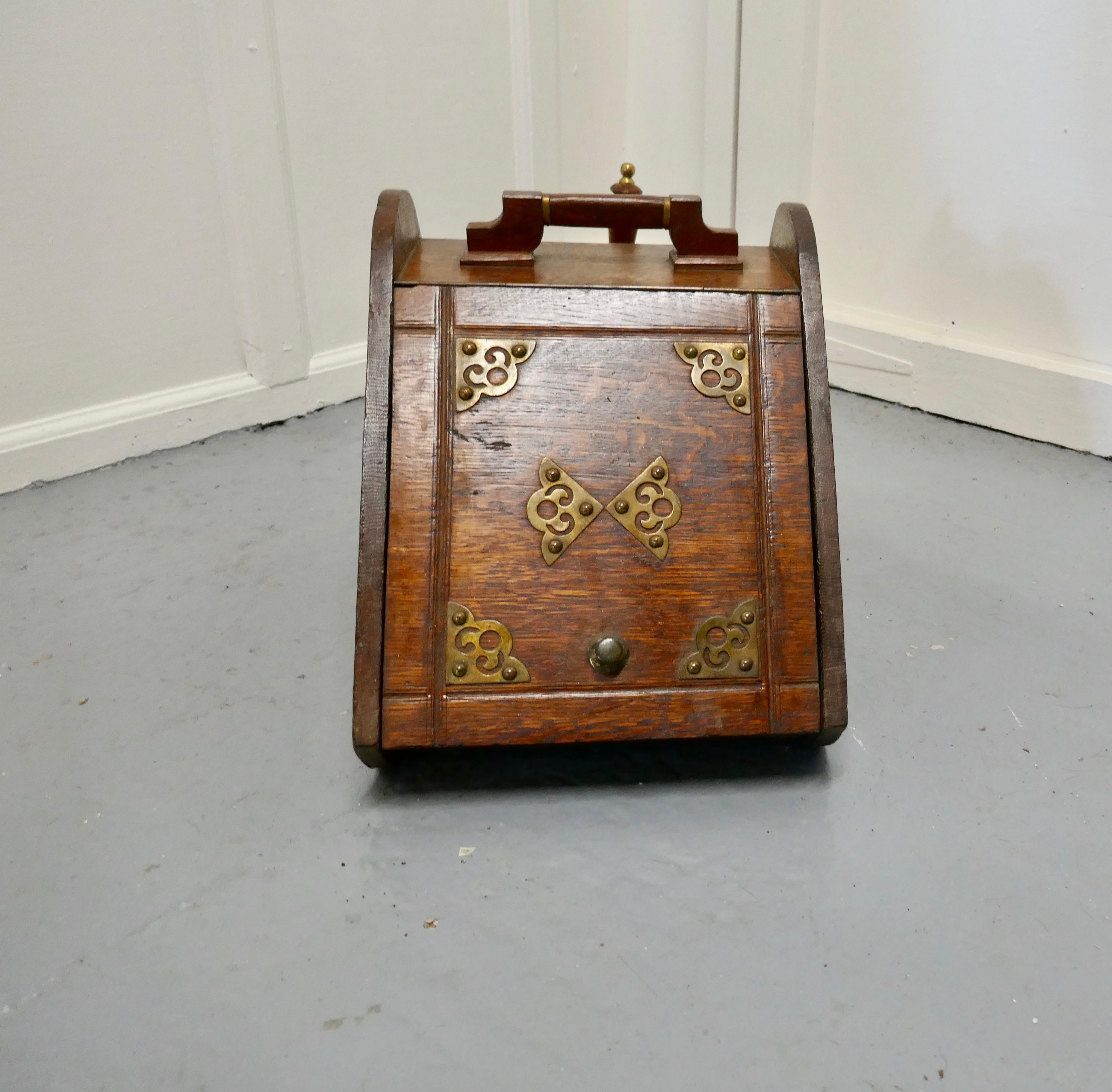 A Victorian oak coal box with liner and shovel

A charming piece of useful Victorian furniture
It has sloping front and back with a decorative brass detail on the front, and a shovel holder in the back and inside a 2 handled metal liner 
It is in