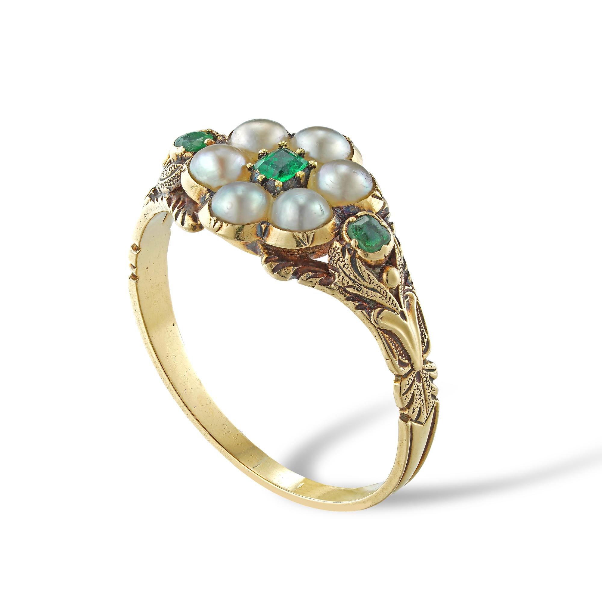 A Victorian pearl and emerald mourning ring, the octagonal-cut emerald surrounded by six half-pearls set in the form of flower petals, to the back a hair locket compartment, each shoulder set with a smaller emerald, the shank engraved with foliate