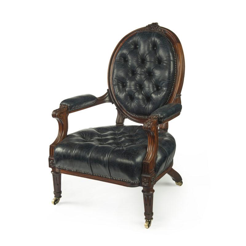 A Victorian rosewood medallion backed open arm chair by Holland & Sons, the rounded back and seat raised upon stop fluted front legs and kicked out back legs, reupholstered in distressed blue leather, buttoned front and back, stamped Holland & Sons