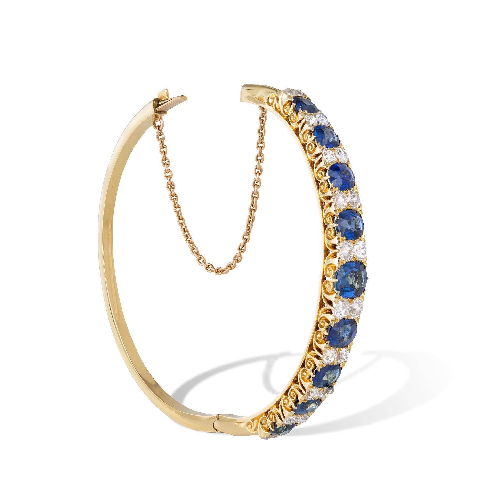 A Victorian sapphire and diamond carved half hoop bangle, the nine oval-cut faceted sapphires weighing approximately 6.8 carats alternatively set with ten vertical rows of two round old brilliant-cut diamonds in-between weighing an estimated total