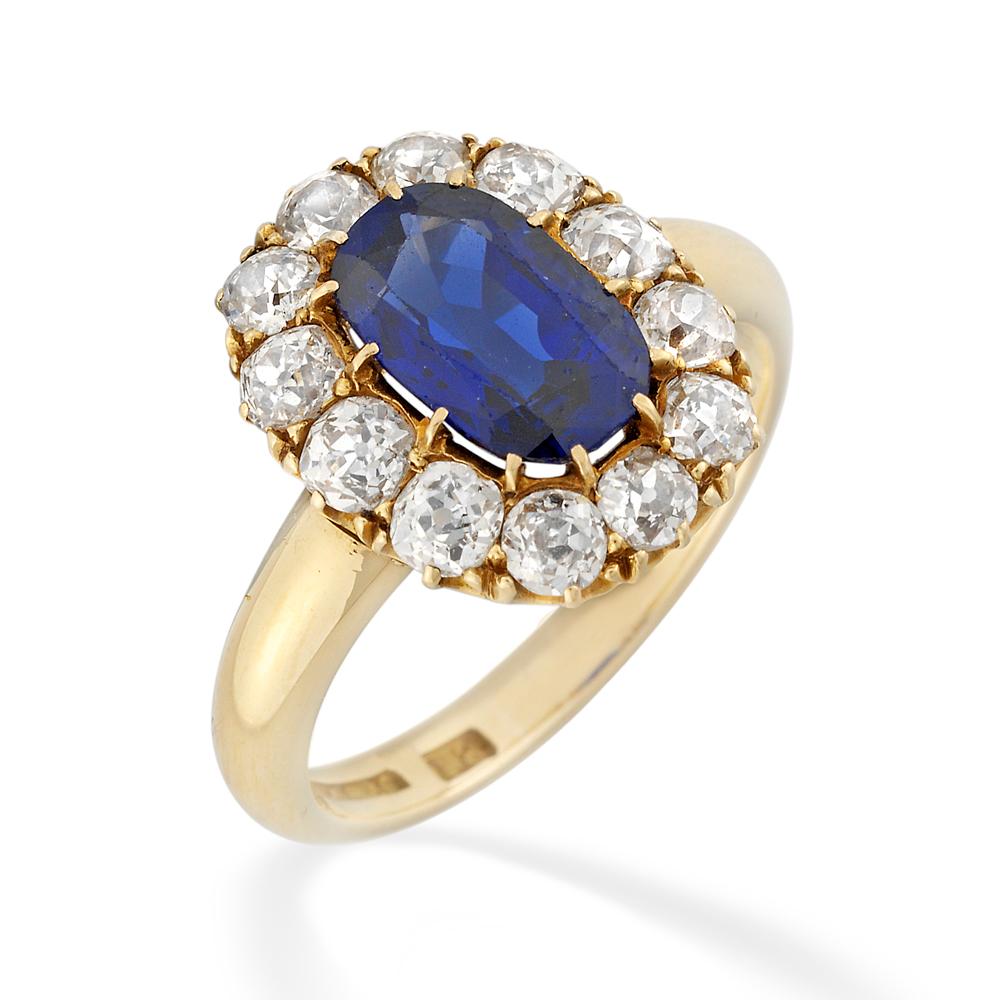 A Victorian sapphire and diamond cluster ring, the oval sapphire measuring approximately 10.55 x 6.50 x 4.00mm and weighing 2.71 carats accompanied by GCS report stating the stone to be of Burmese origin with no indications of heating, 12 claw set