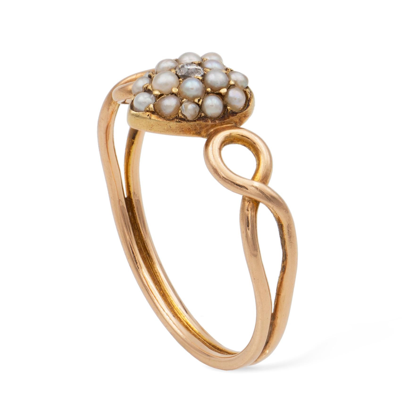 A Victorian seed pearl and diamond heart ring, the heart set with an old European-cut diamond surrounded by seventeen seed pearls, to openwork entwinned shoulders with a double wire-typed shank, stamped 15ct gold on the heart’s back, circa 1890,