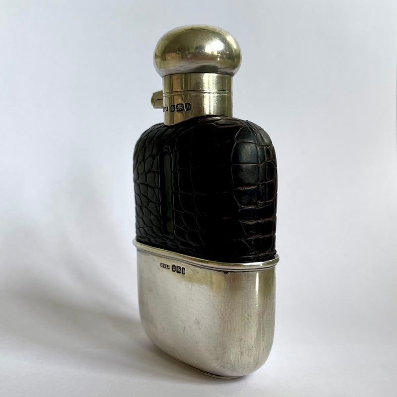 A beautiful English sterling sliver and crocodile late Victorian antique hip flask.

Mounted with a precision made domed top with a smooth hinge and bayonet fitting and retaining its original cork stopper. 

The the sterling silver drinking cup