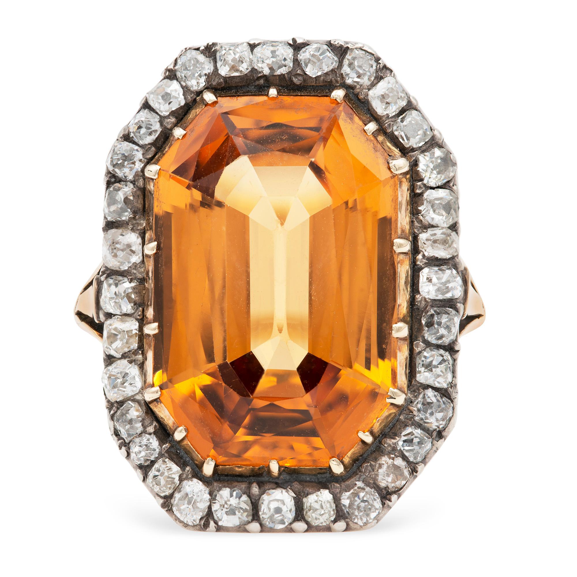 A Victorian topaz and diamond cluster ring, the octagonal-cut orange topaz measuring approximately 18.8 x 12.75 x 7.4mm and estimated to weigh 13.1 carats cut down set in gold collet, surrounded by old cut diamonds estimated to weigh 0.95 carats in