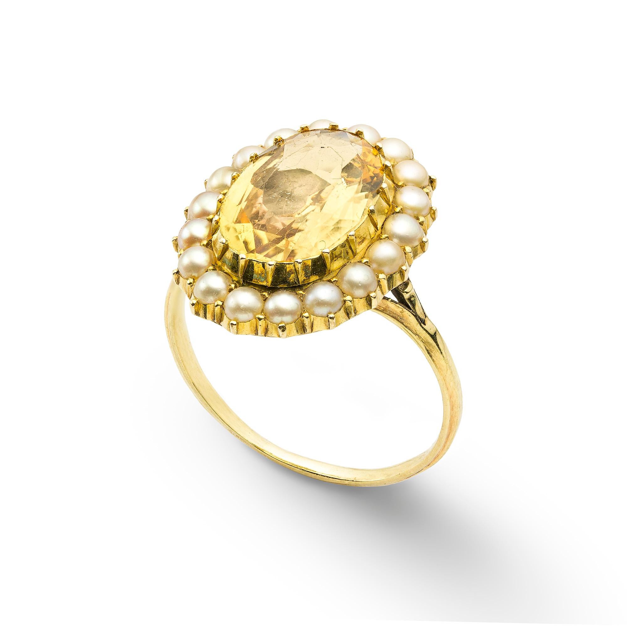 A Victorian topaz and pearl cluster ring, the oval faceted golden topaz, estimated to weigh 4 carats, to a surround of eighteen half pearls, in cut down settings to a gold mount with split shoulders, circa 1850, the head measuring approximately size