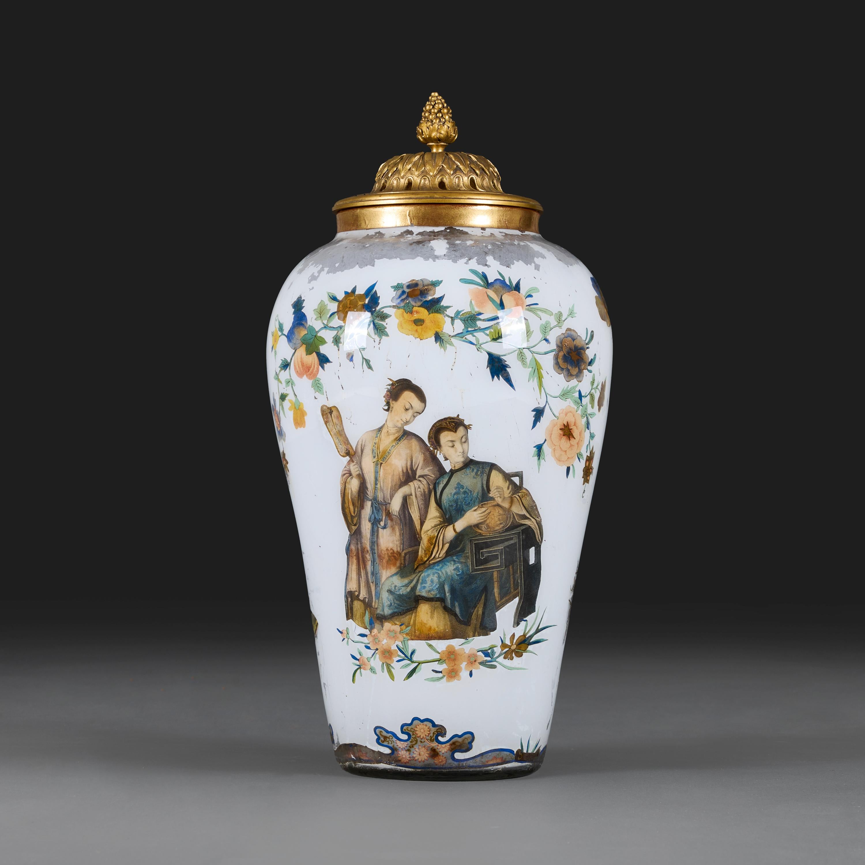 England, circa 1880.

A late nineteenth century Victorian Decalcomania glass baluster vase decorated with Chinese figures, floral sprays and butterflies on a white ground, mounted with a pierced fire gilt lid surmounted with an grape cluster