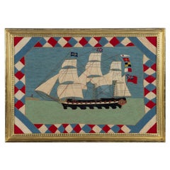 A Victorian wool picture of a three masted frigate flying several flags and ensi