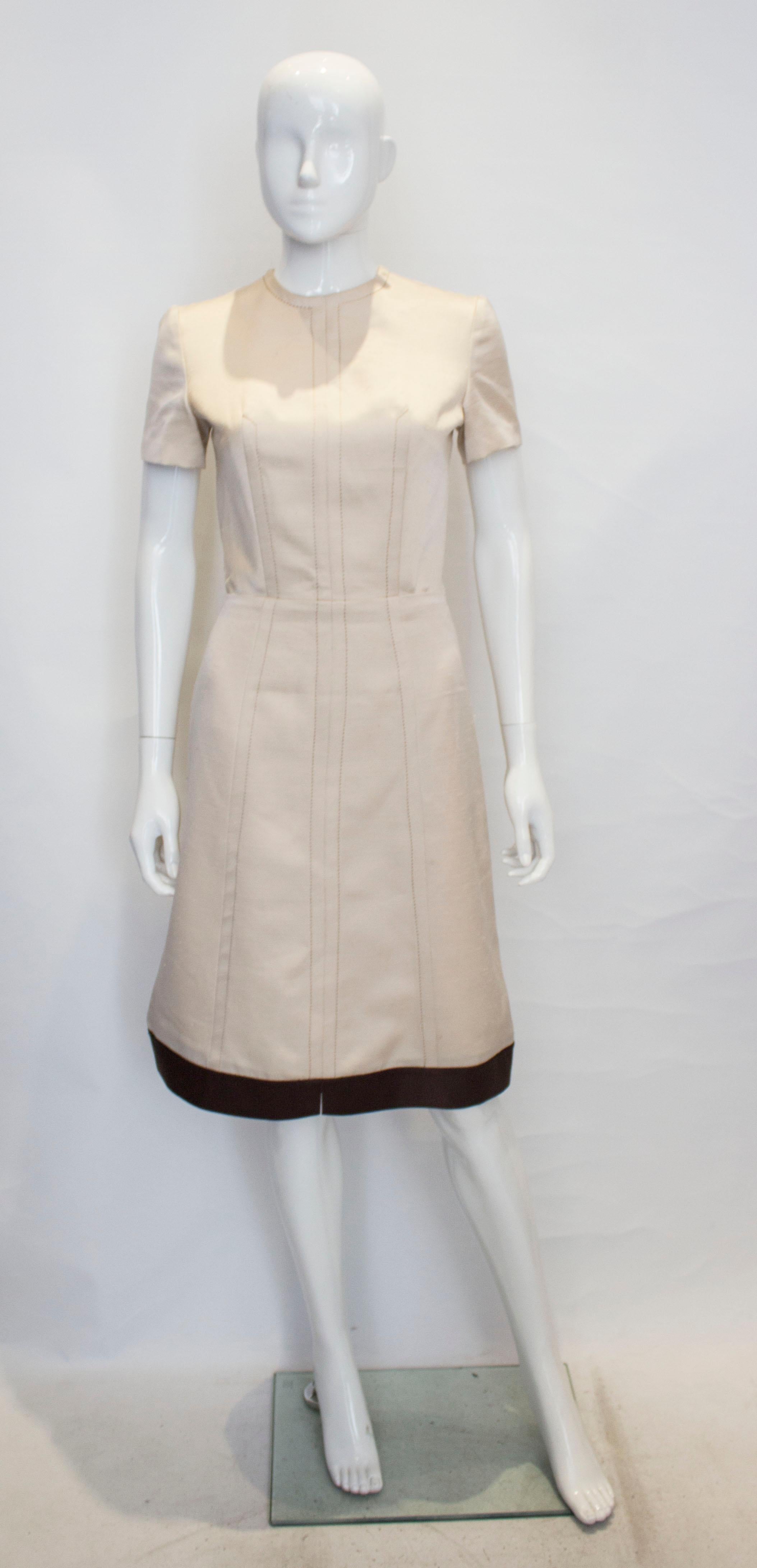 A vintage 1960s cream fitted raw silk dress with a brown silk hem 

fitted at the waist zips up the back with a interesting stitch detail across the bodice

measurements taken flat in inches 

bust - 16
waist - 13
length - 41