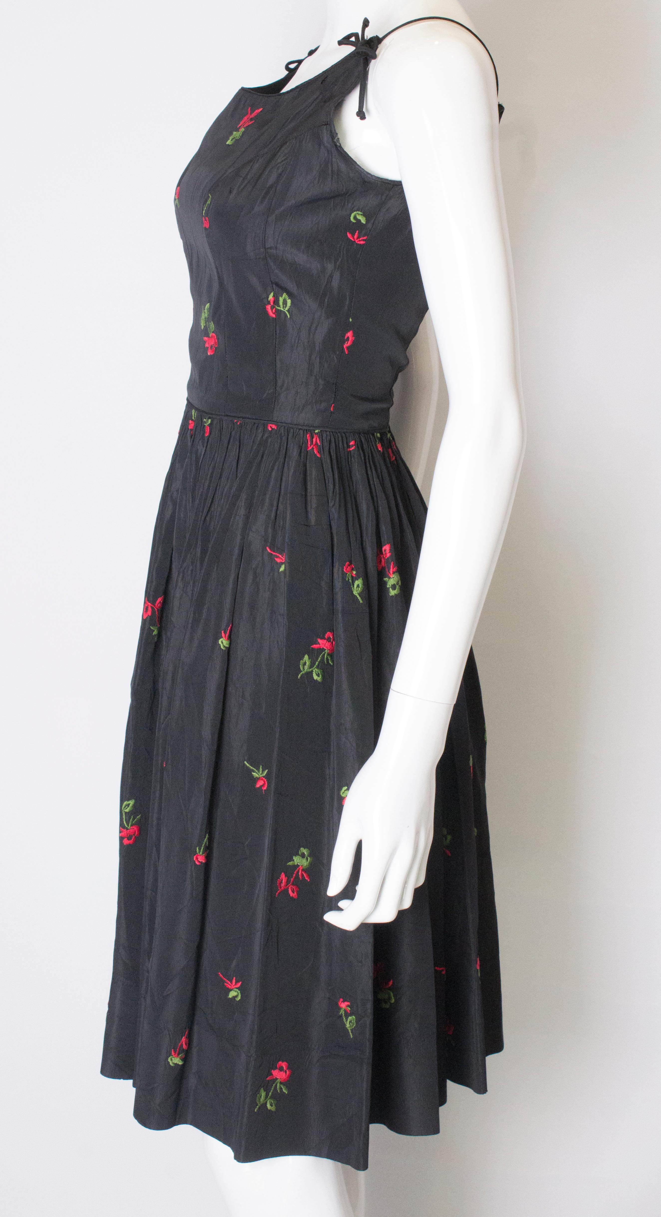 Women's A vintage 1950s black cinch swing dress with embroidered flowers 
