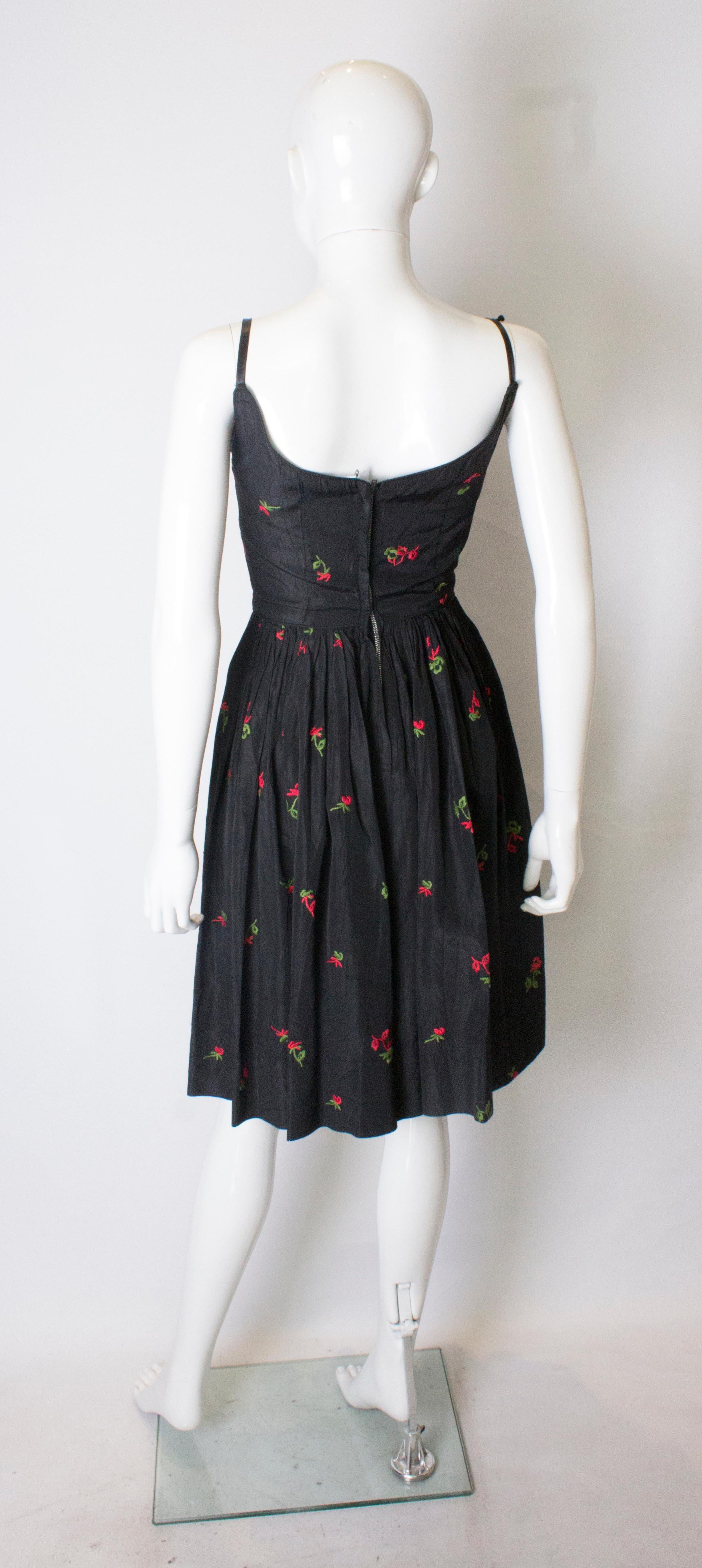 A vintage 1950s black cinch swing dress with embroidered flowers  1
