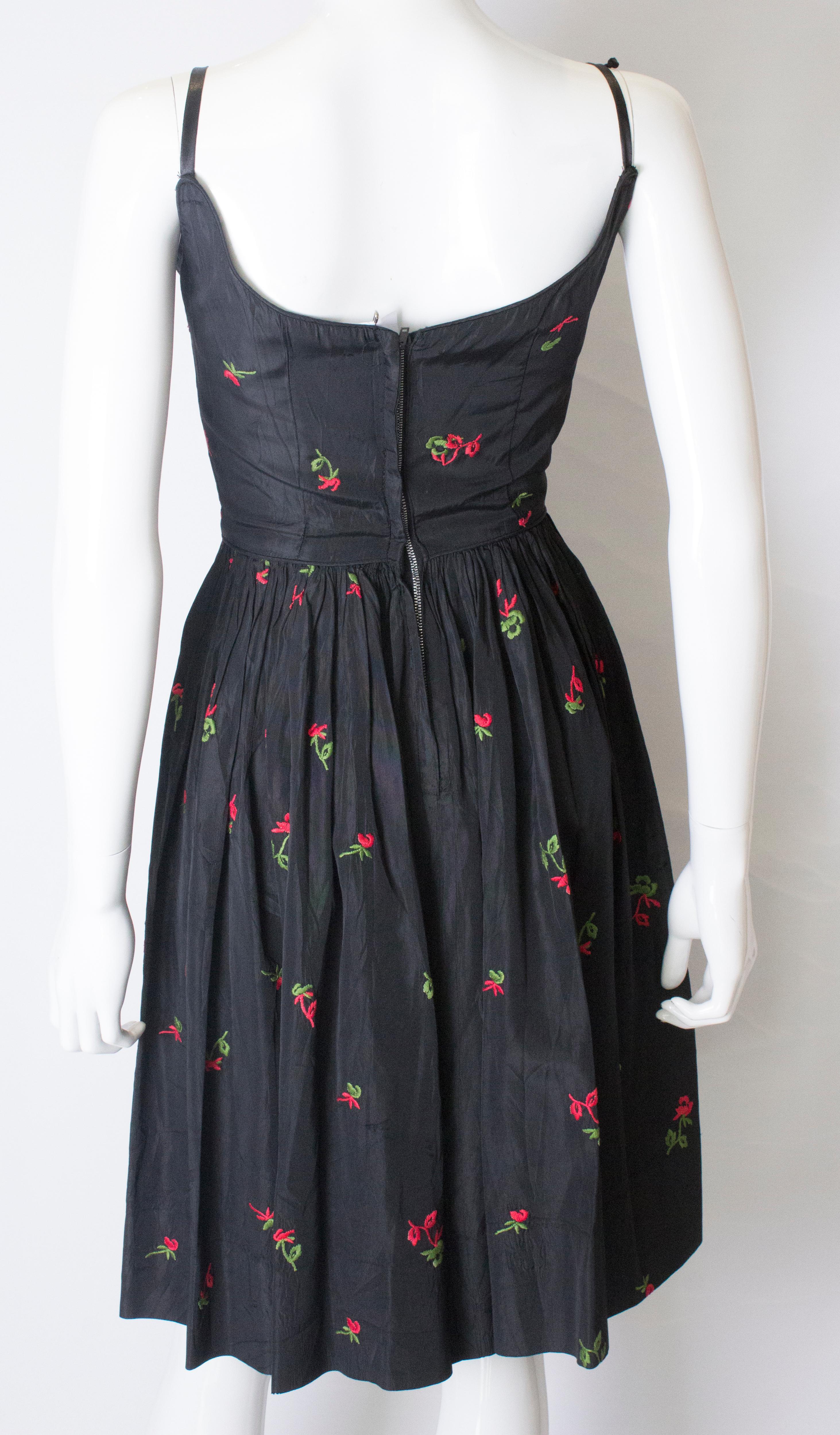 A vintage 1950s black cinch swing dress with embroidered flowers  2