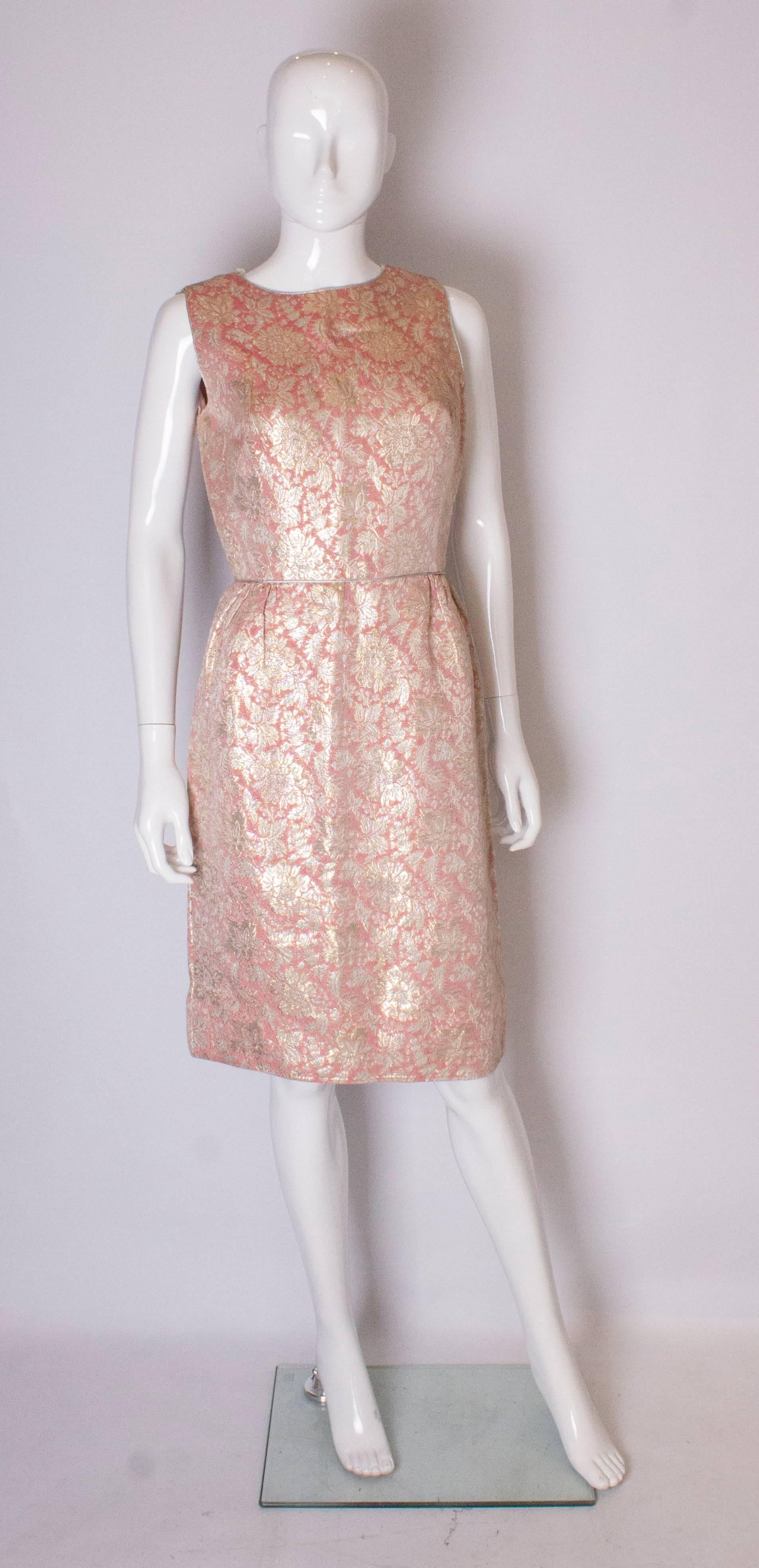 A gold , silver and pink  metallic vintage cocktail dress with silver trim . The dress is gathered at the waist and has a central back zip. It has a three and a half inch hem