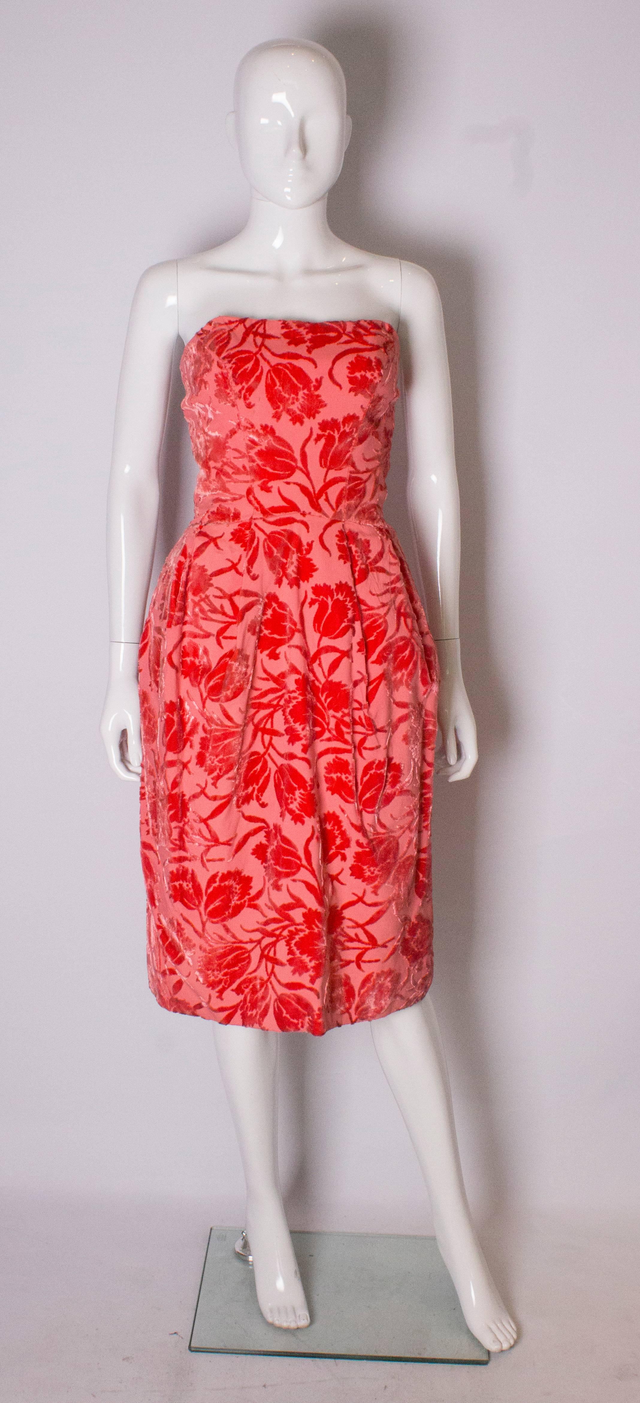 A pretty vintage party dress in a coral pink coloured devore velvet. The dress is boned at the bust area, has a tulip shape skirt, and  is fully lined,with a central back zip.

